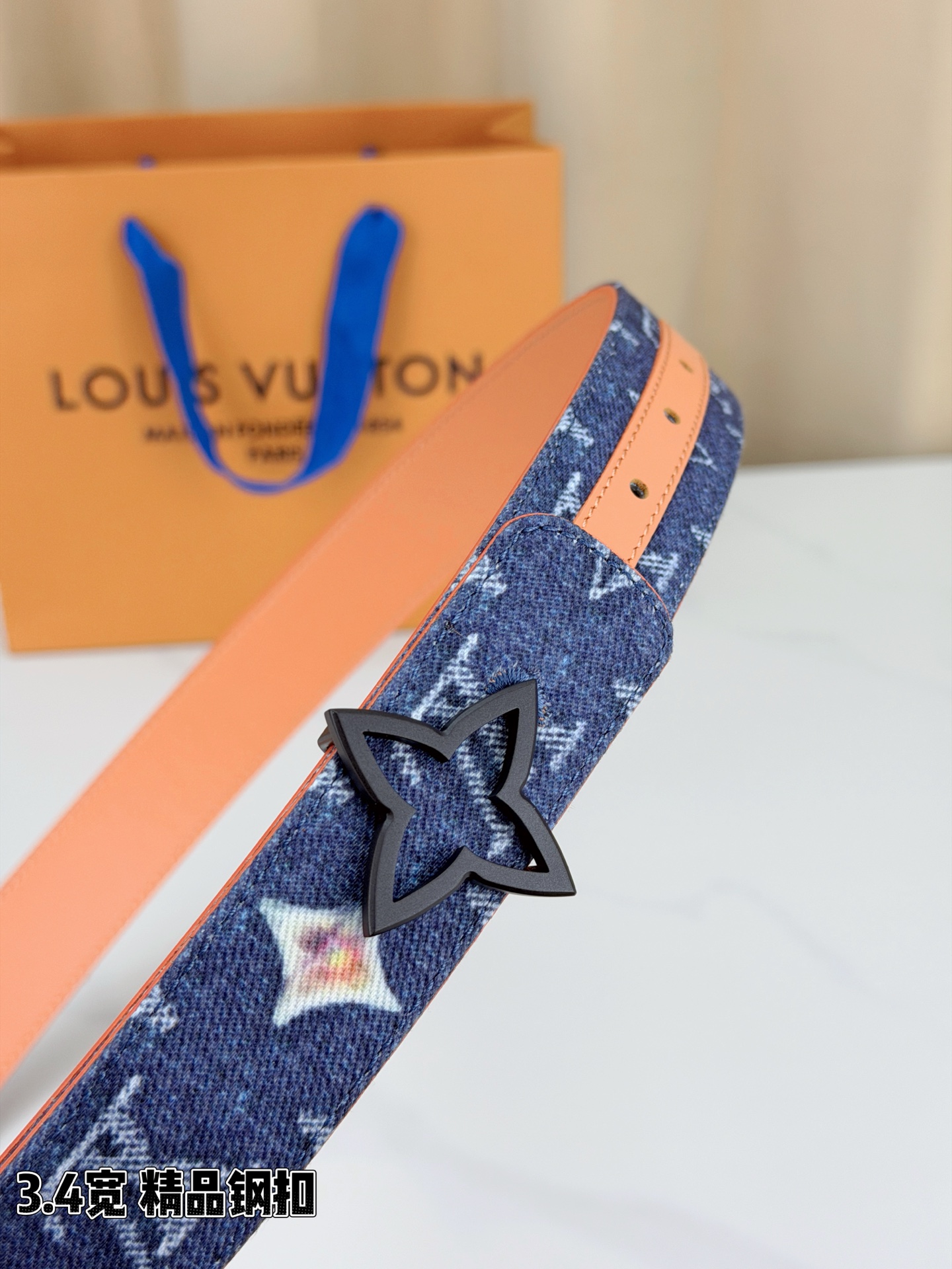 路易威登3.4宽精品钢扣腰带，深蓝牛仔邂逅经典老花，白色LV印记与浅橙花朵交相辉映。镂空四叶花扣金色华贵