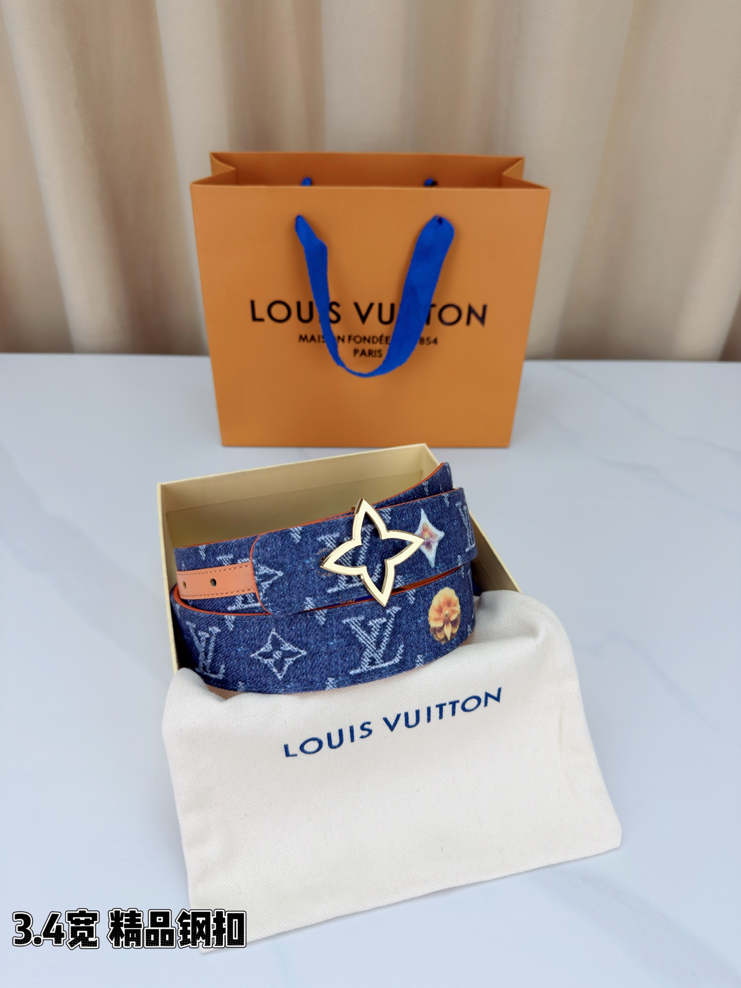 路易威登3.4宽精品钢扣腰带，深蓝牛仔邂逅经典老花，白色LV印记与浅橙花朵交相辉映。镂空四叶花扣金色华贵