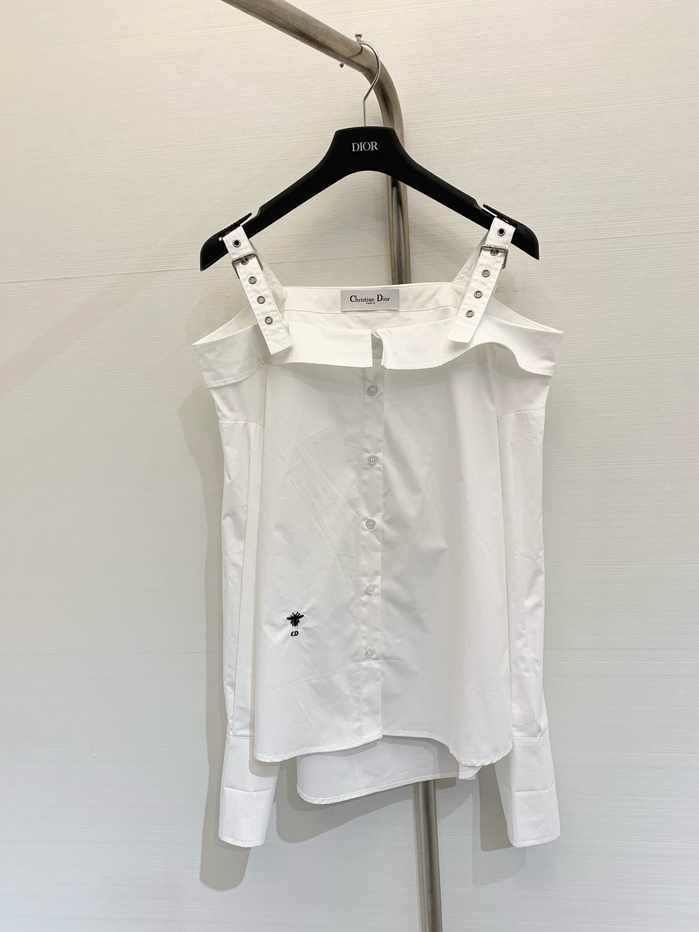 NO:325687,Dior 2025 summer new style, one-shoulder suspender shirt, customized YB twill cotton material, comfortable and delicate texture, one-shoulder suspender shirt style, neatly cut, matched with perforated shoulder straps with a sense of workwear, cleverly blending sweetness and handsome style, revealing the collarbone to make it look fashionable, loose hem to accommodate the body shape, add CD bee logo decoration at waist, brand texture is full of exquisite atmosphere, exquisite moment, basic shirt that can be used for daily commuting and vacation, color white, black, SML, dior,shirts,alexander wang19860909Dior 2025 夏季新款 一字肩吊带衬衣,定制YB斜纹全棉材质 质感舒适细腻 一字肩吊带衬衫版型 裁剪利落 搭配工装感十足的穿孔肩带 巧妙融合甜美和帅气风格 露出锁骨更显时髦气息 宽松下摆起到包容身材的廓形效果 腰间增加CD蜜蜂徽标装饰 品牌质感充满精致气息 精致度瞬间 日常通勤度假都可驾驭的基础衬衫 颜色白色 黑色 码数SML,,dior,shirts,alexander wang,Women's clothing