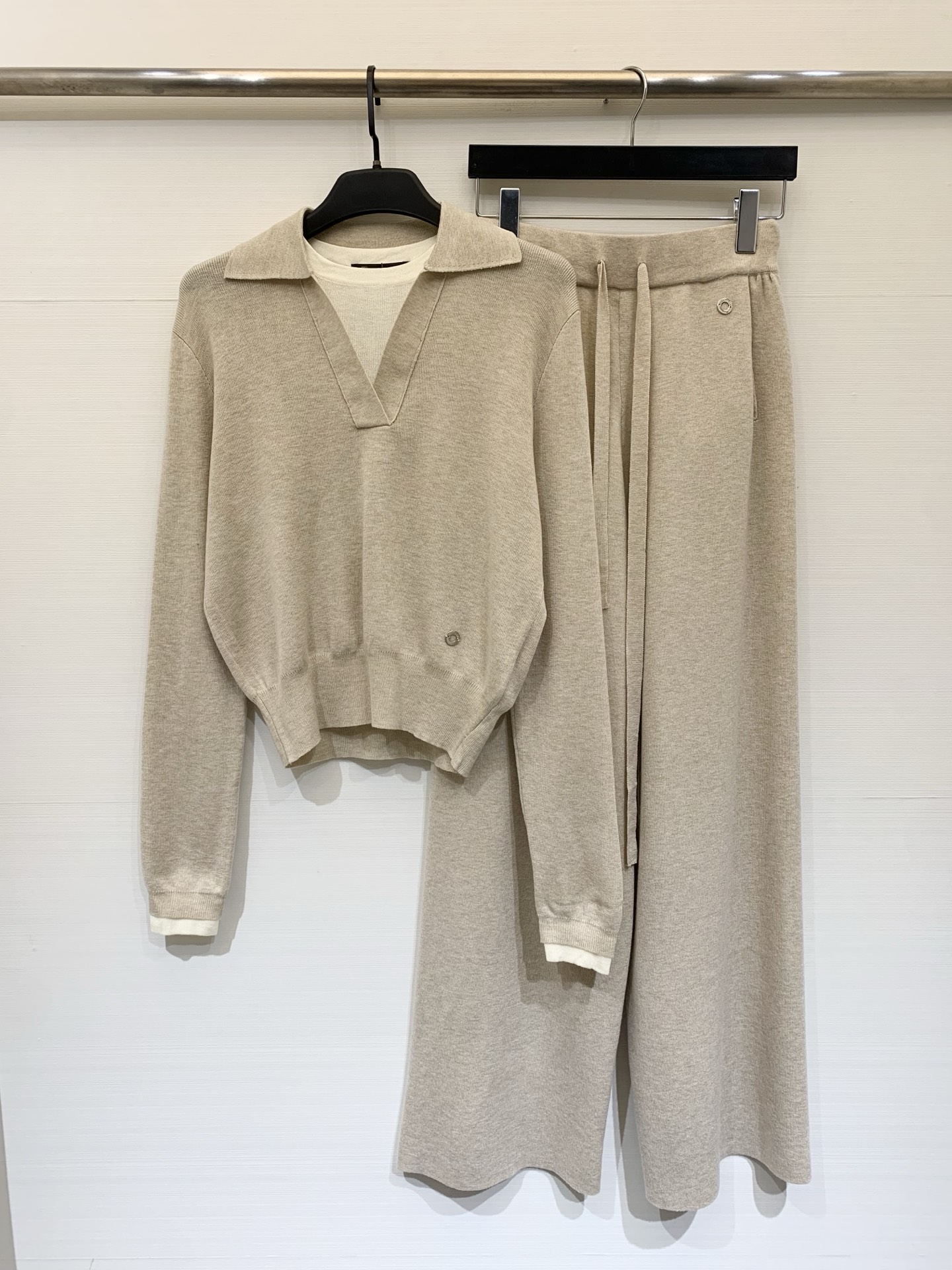 NO:708667,360L 26 early spring new style  The knitted suit is made of delicate and soft knitted fabrics. The fake two-piece lapel sweater and wide-leg knitted trousers have a loose and lazy silhouette as a whole, showing a gentle and advanced casual temperament. The top has an olo collar with a V-shaped placket and a fake two-piece design. The dropped shoulder sleeves are cut to modify the shoulder line, and the short version raises the waistline; the white contrasting edge on the hem and cuffs adds a layer of detail, and the metal buttons on the side  The embellishment enhances the sense of sophistication. The bottoms are high-waisted wide-leg knitted trousers with a drawstring waistband that adapts to a variety of waistlines. The drapey trouser legs modify the leg lines and form a visual unity with the tops in the same color. The whole outfit is soft and skin-friendly without losing shape. Whether it is for home leisure or daily outings, you can easily create a simple and elegant style. Two-color SML, loro  piana,19860909360L 26早春新款 针织套装,采用细腻软糯的针织面料,假两件翻领针织衫阔腿针织长裤,整体为宽松慵懒的廓形,尽显温柔高级的休闲气质,上衣是olo领搭配V字开襟假两件设计,落肩袖剪裁修饰肩线,短款版型拉高腰线；下摆与袖口的白色撞色边增添细节层次,侧边的金属纽扣点缀提升精致感.下装是高腰阔腿针织裤,抽绳腰头适配多种腰围,垂坠感十足的裤腿修饰腿部线条,与上衣同色系的搭配形成视觉统一.整套穿搭柔软亲肤又不失版型,无论是居家休闲还是日常出街,都能轻松打造出简约大气的温柔风造型.两色SML,,loro piana,,Women's clothing