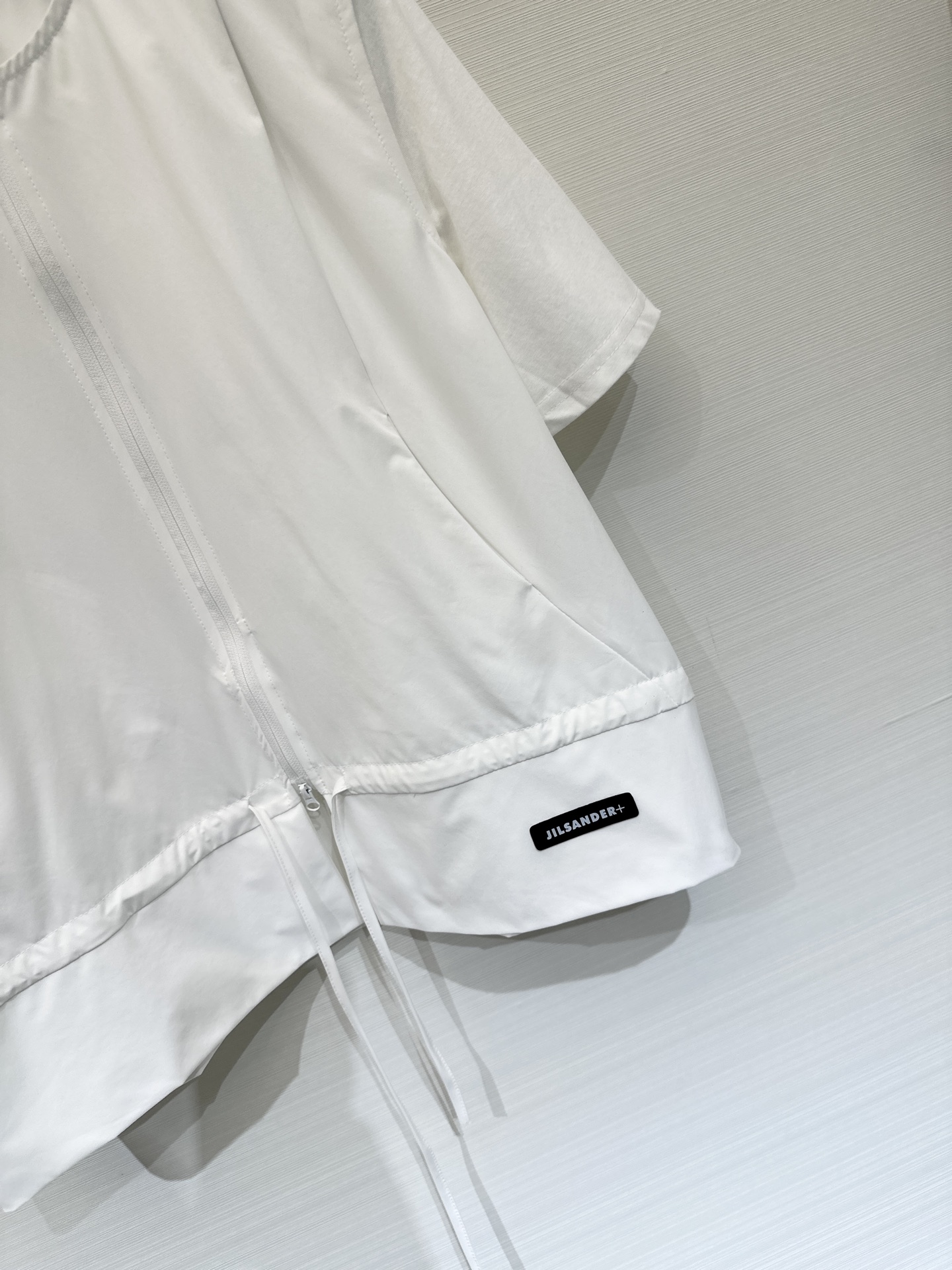 JILSANDER+ 26春夏新款 拼接拉链短袖上衣，极简高级风，采用双向拉链贯穿前襟，下摆设有抽绳设计