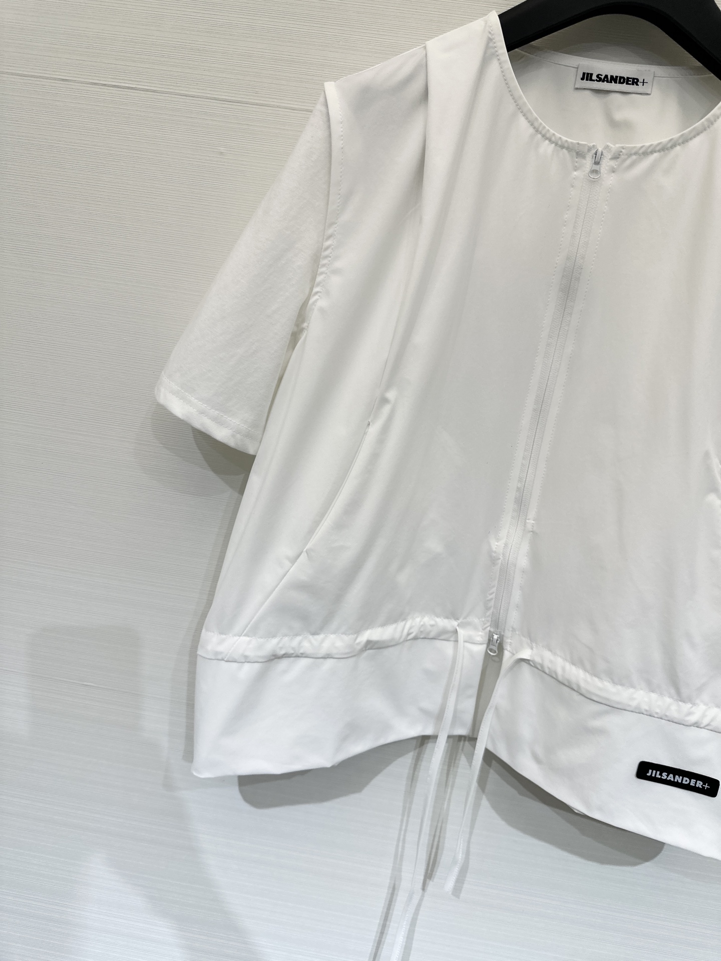 JILSANDER+ 26春夏新款 拼接拉链短袖上衣，极简高级风，采用双向拉链贯穿前襟，下摆设有抽绳设计