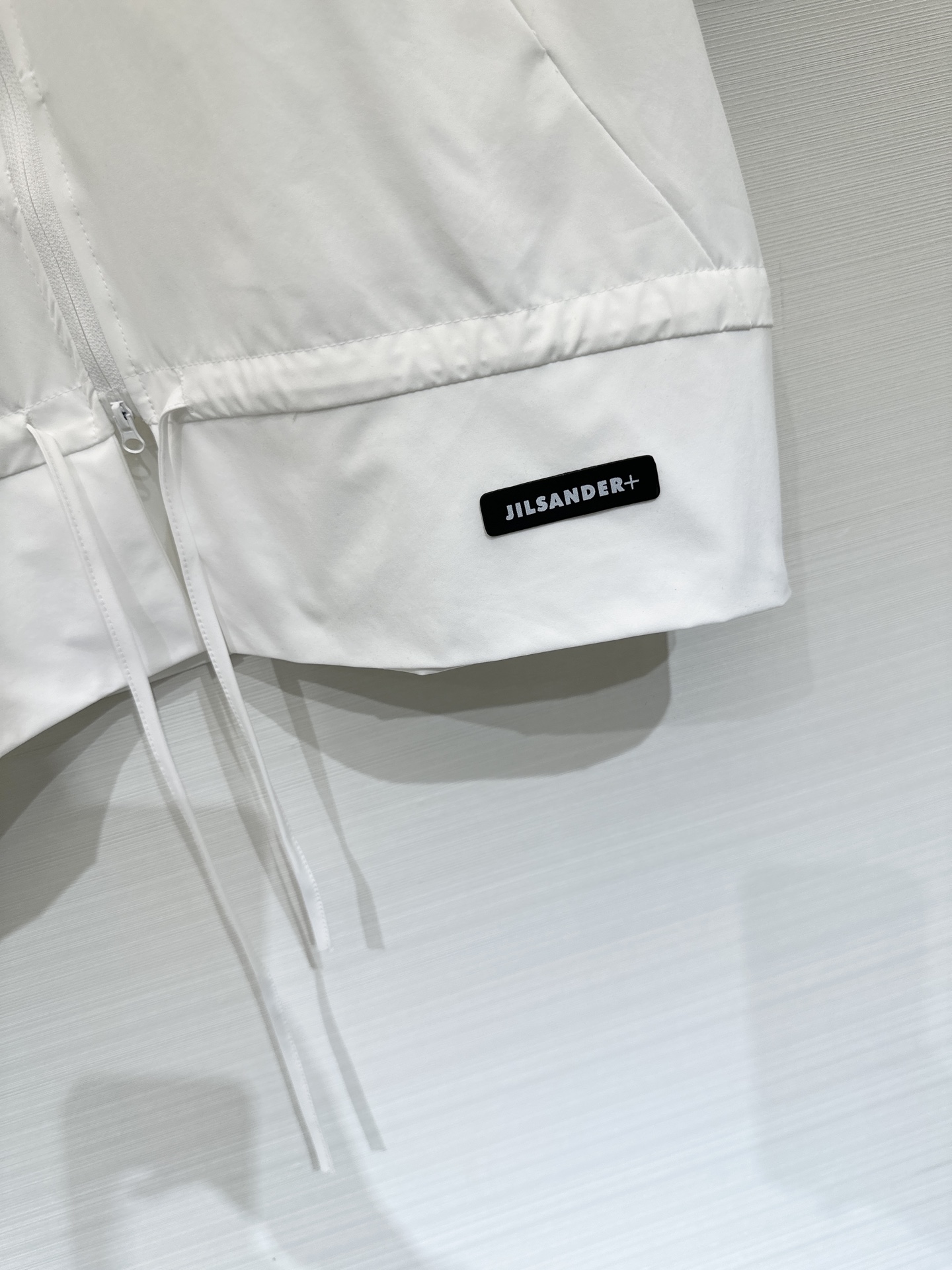 JILSANDER+ 26春夏新款 拼接拉链短袖上衣，极简高级风，采用双向拉链贯穿前襟，下摆设有抽绳设计