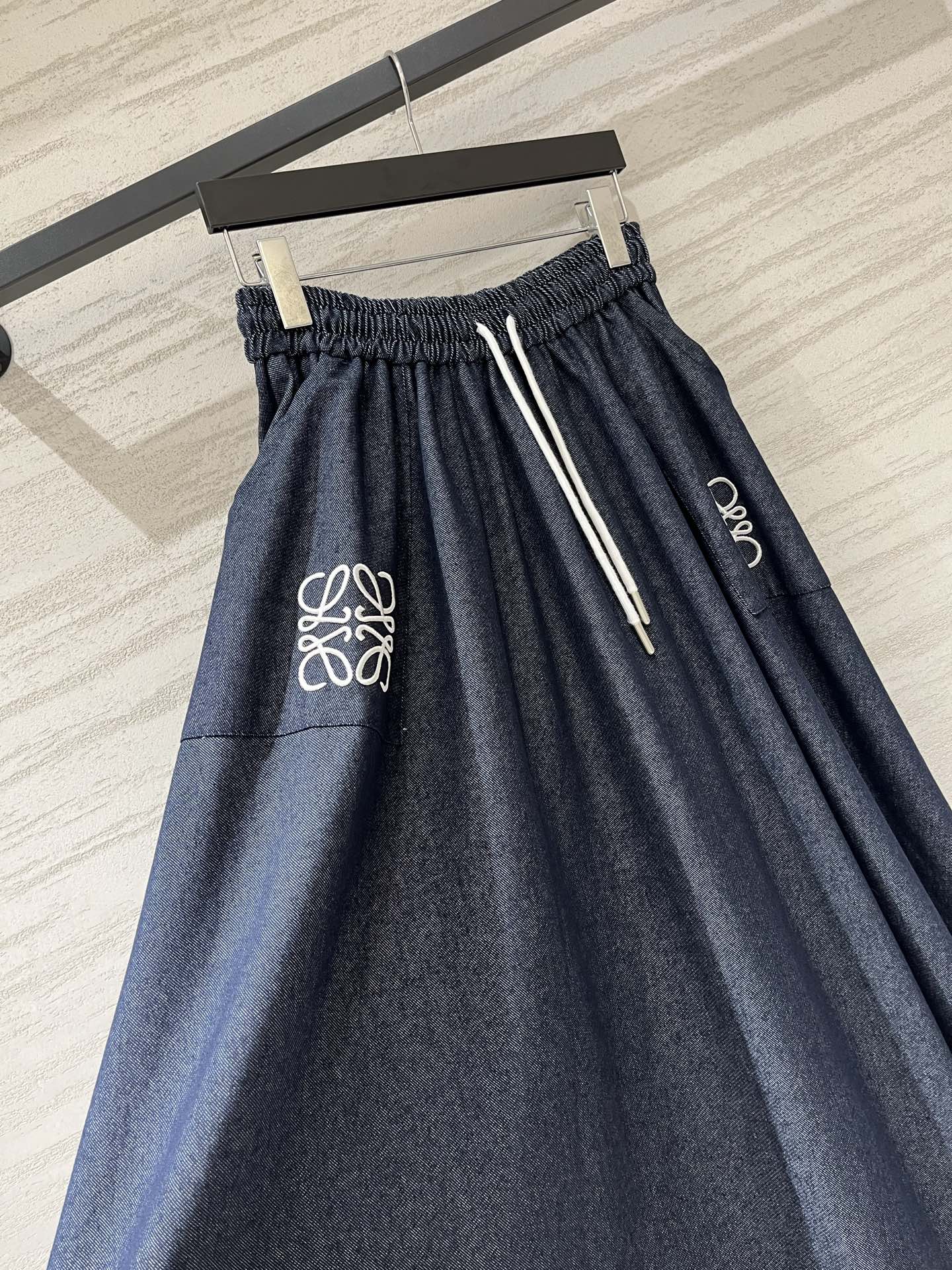 Loewe 牛仔质感A字半裙，采用品牌标志性的Anagram刺绣为设计亮点，藏青色牛仔面料搭配白色刺绣，