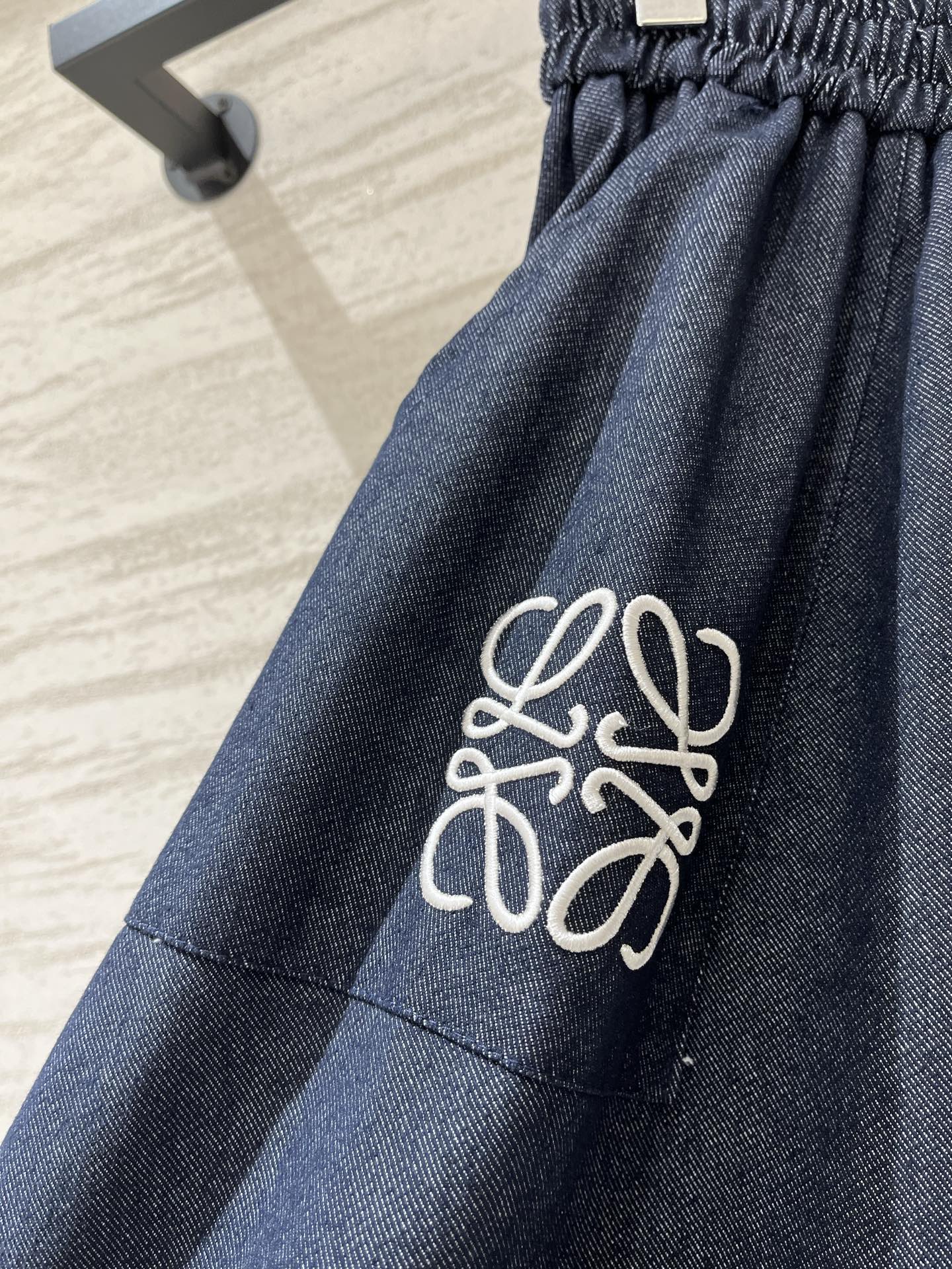 Loewe 牛仔质感A字半裙，采用品牌标志性的Anagram刺绣为设计亮点，藏青色牛仔面料搭配白色刺绣，