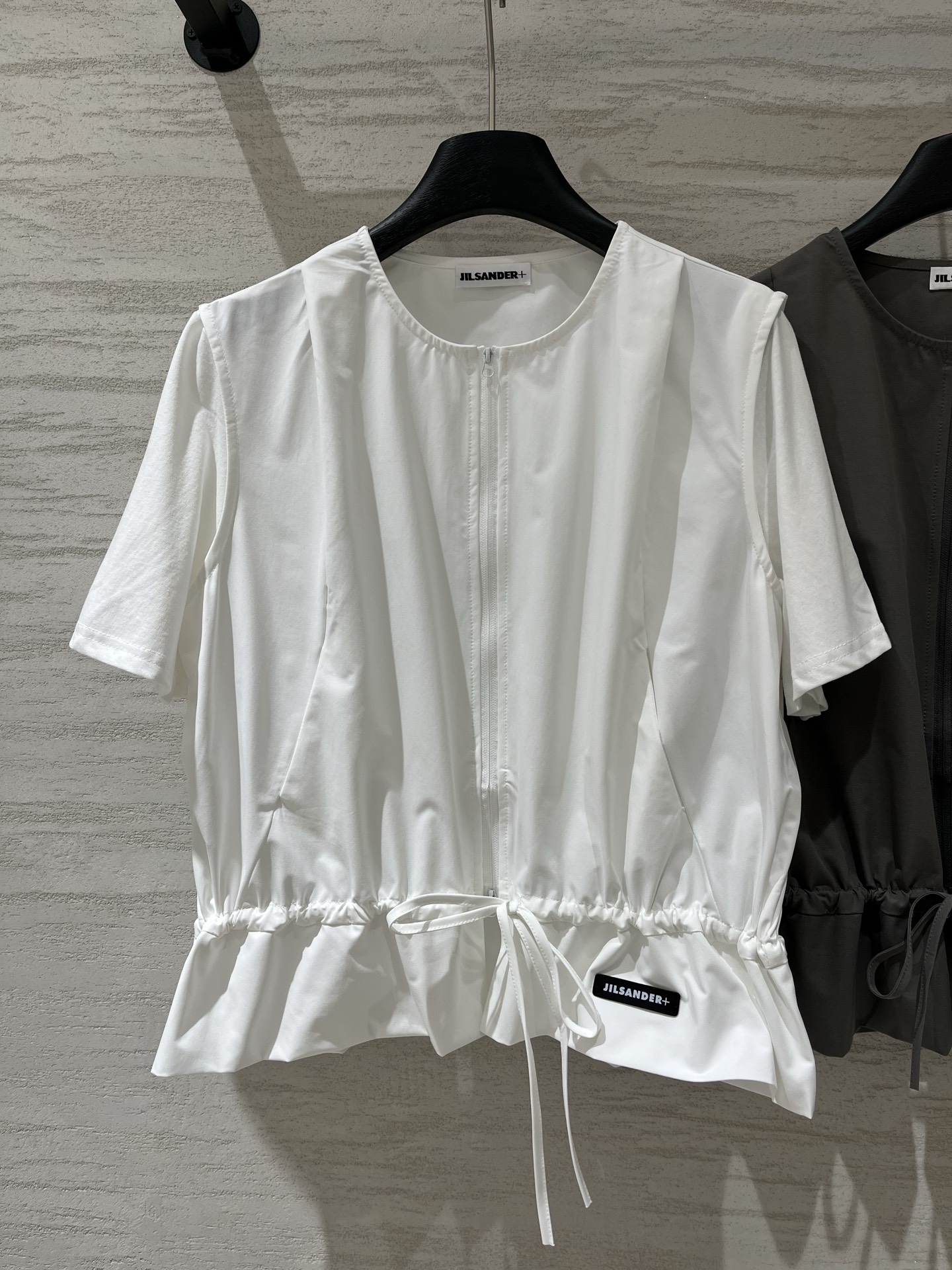 NO:932508,JILSANDER+ 26 Spring and Summer New Style  Spliced zipper short-sleeved top, minimalist high-end style, with a two-way zipper running through the front, and a drawstring design at the hem, which can be freely adjusted to loosen up and shape the waist. The main part is made of crisp and smooth windbreaker nylon fabric, with a sense of drape; the sleeves are spliced with pure cotton, and have a loose A-line version, which is tolerant to the body and can well modify the shoulder width and waist and abdomen lines. Two-color SM,, jil sander, T-shirt,19860909JILSANDER+ 26春夏新款 拼接拉链短袖上衣,极简高级风,采用双向拉链贯穿前襟,下摆设有抽绳设计,可自由调节宽松度,既能随性松弛也能收腰定型,主体部分选用挺括顺滑的风衣尼龙面料,自带垂坠感；袖子部分拼接纯棉,宽松A字版型,对身材包容性强,能很好地修饰肩宽与腰腹线条两色SM,,jil sander,T-shirt,,Women's clothing