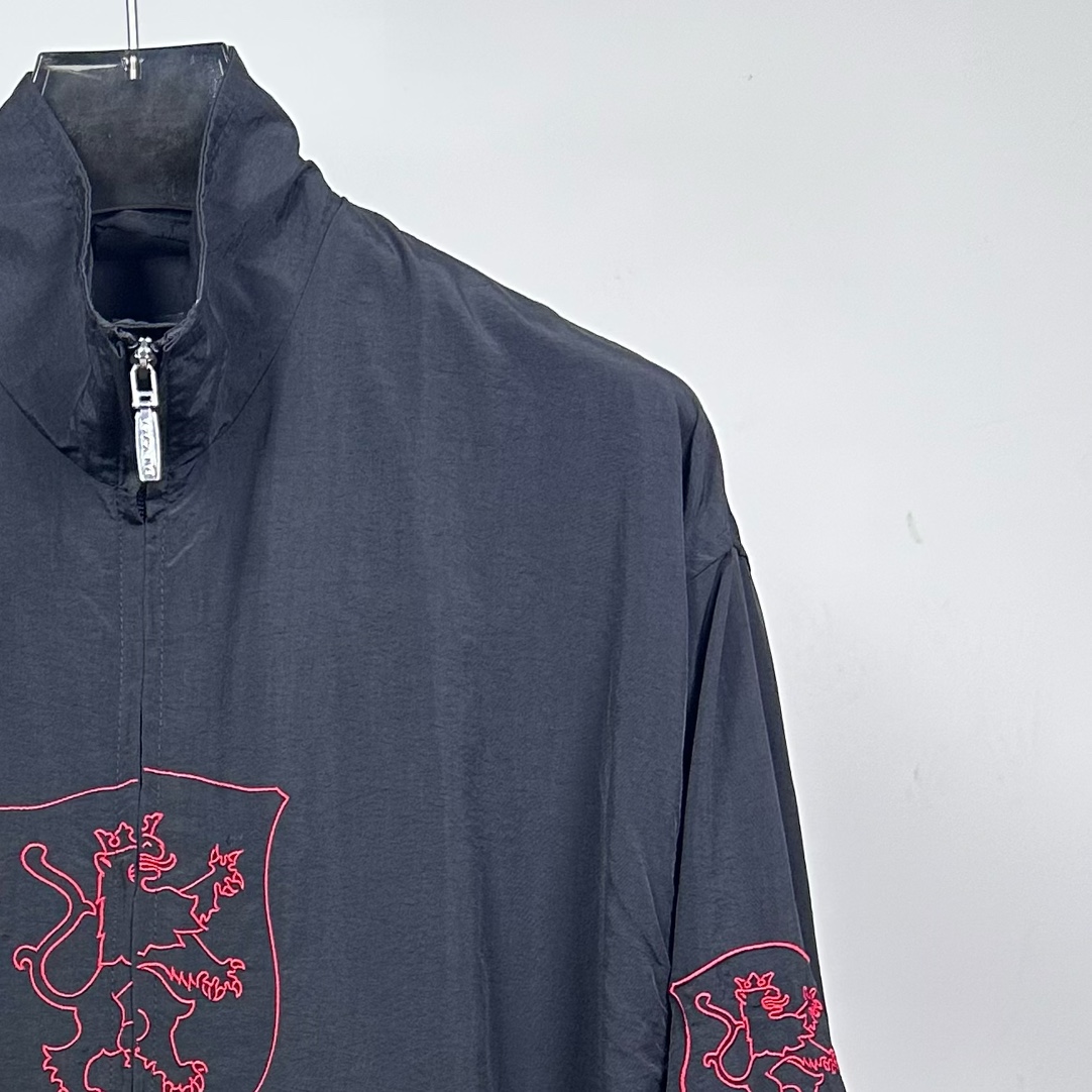 P240
款号：Y08
Balenciaga 巴黎世家新款lion club曼联运动冲锋衣外套-

酷盖必备💥| Balenciaga 曼联刺绣冲锋衣
👦潮流玩家们，Balenciaga 这件黑色曼联刺绣冲锋衣真的杀疯了！
⚫经典黑色，百搭王者段位，怎么搭都不出错，轻松拿捏各种风格。冲锋衣版型挺括有型，穿上身气场瞬间两米八，户外感与时尚感并存。
曼联刺绣无疑是最大亮点👏，传承足球精神的同时，为这件冲锋衣赋予了独特的文化底蕴，精致刺绣在黑色基底上格外惹眼，高级感与个性齐飞。
功能性更是杠杠的👍，专业防水面料，下雨天、户外探险都能应对自如；透气设计让你运动出汗后也能保持干爽。拉链顺滑无阻，多口袋方便收纳随身小物件。 
尺码：S-XL 