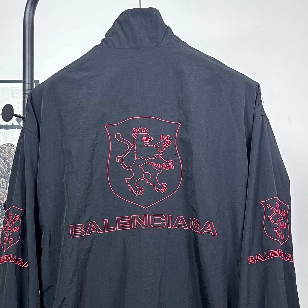 P240
款号：Y08
Balenciaga 巴黎世家新款lion club曼联运动冲锋衣外套-

酷盖必备💥| Balenciaga 曼联刺绣冲锋衣
👦潮流玩家们，Balenciaga 这件黑色曼联刺绣冲锋衣真的杀疯了！
⚫经典黑色，百搭王者段位，怎么搭都不出错，轻松拿捏各种风格。冲锋衣版型挺括有型，穿上身气场瞬间两米八，户外感与时尚感并存。
曼联刺绣无疑是最大亮点👏，传承足球精神的同时，为这件冲锋衣赋予了独特的文化底蕴，精致刺绣在黑色基底上格外惹眼，高级感与个性齐飞。
功能性更是杠杠的👍，专业防水面料，下雨天、户外探险都能应对自如；透气设计让你运动出汗后也能保持干爽。拉链顺滑无阻，多口袋方便收纳随身小物件。 
尺码：S-XL 