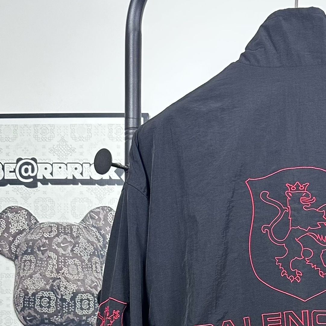 P240
款号：Y08
Balenciaga 巴黎世家新款lion club曼联运动冲锋衣外套-

酷盖必备💥| Balenciaga 曼联刺绣冲锋衣
👦潮流玩家们，Balenciaga 这件黑色曼联刺绣冲锋衣真的杀疯了！
⚫经典黑色，百搭王者段位，怎么搭都不出错，轻松拿捏各种风格。冲锋衣版型挺括有型，穿上身气场瞬间两米八，户外感与时尚感并存。
曼联刺绣无疑是最大亮点👏，传承足球精神的同时，为这件冲锋衣赋予了独特的文化底蕴，精致刺绣在黑色基底上格外惹眼，高级感与个性齐飞。
功能性更是杠杠的👍，专业防水面料，下雨天、户外探险都能应对自如；透气设计让你运动出汗后也能保持干爽。拉链顺滑无阻，多口袋方便收纳随身小物件。 
尺码：S-XL 