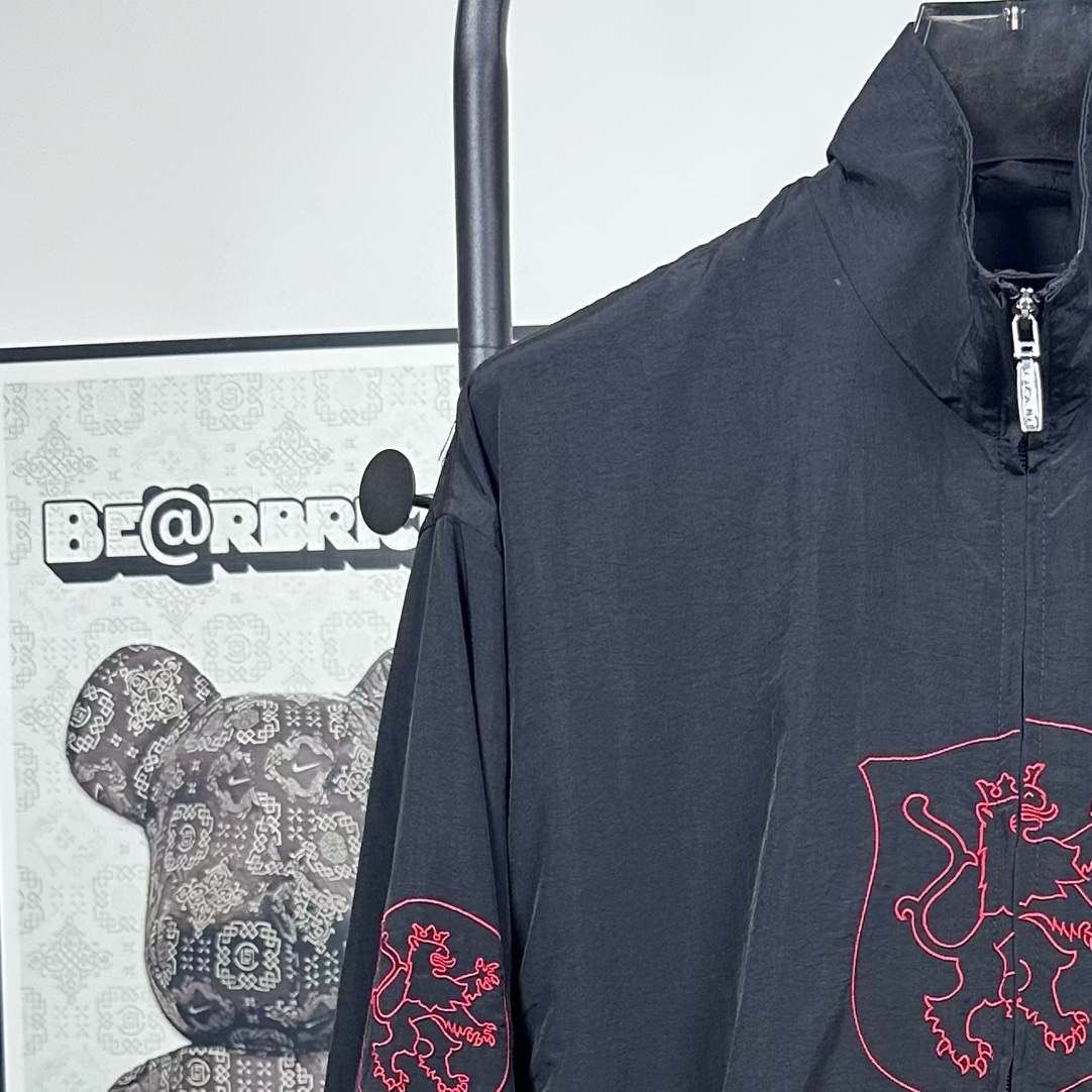 P240
款号：Y08
Balenciaga 巴黎世家新款lion club曼联运动冲锋衣外套-

酷盖必备💥| Balenciaga 曼联刺绣冲锋衣
👦潮流玩家们，Balenciaga 这件黑色曼联刺绣冲锋衣真的杀疯了！
⚫经典黑色，百搭王者段位，怎么搭都不出错，轻松拿捏各种风格。冲锋衣版型挺括有型，穿上身气场瞬间两米八，户外感与时尚感并存。
曼联刺绣无疑是最大亮点👏，传承足球精神的同时，为这件冲锋衣赋予了独特的文化底蕴，精致刺绣在黑色基底上格外惹眼，高级感与个性齐飞。
功能性更是杠杠的👍，专业防水面料，下雨天、户外探险都能应对自如；透气设计让你运动出汗后也能保持干爽。拉链顺滑无阻，多口袋方便收纳随身小物件。 
尺码：S-XL 