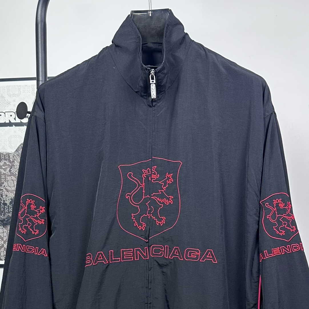 P240
款号：Y08
Balenciaga 巴黎世家新款lion club曼联运动冲锋衣外套-

酷盖必备💥| Balenciaga 曼联刺绣冲锋衣
👦潮流玩家们，Balenciaga 这件黑色曼联刺绣冲锋衣真的杀疯了！
⚫经典黑色，百搭王者段位，怎么搭都不出错，轻松拿捏各种风格。冲锋衣版型挺括有型，穿上身气场瞬间两米八，户外感与时尚感并存。
曼联刺绣无疑是最大亮点👏，传承足球精神的同时，为这件冲锋衣赋予了独特的文化底蕴，精致刺绣在黑色基底上格外惹眼，高级感与个性齐飞。
功能性更是杠杠的👍，专业防水面料，下雨天、户外探险都能应对自如；透气设计让你运动出汗后也能保持干爽。拉链顺滑无阻，多口袋方便收纳随身小物件。 
尺码：S-XL 