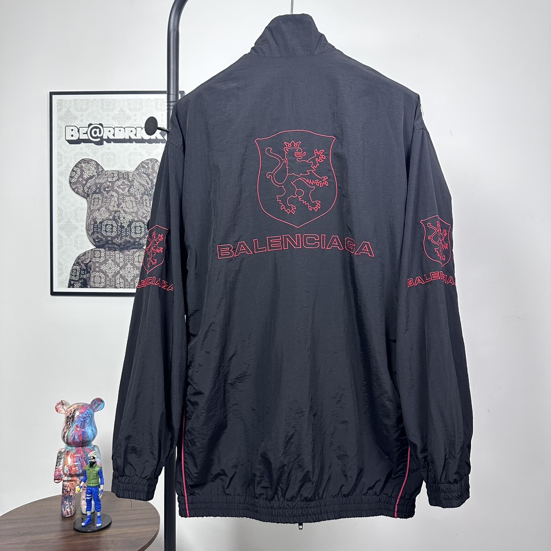 P240
款号：Y08
Balenciaga 巴黎世家新款lion club曼联运动冲锋衣外套-

酷盖必备💥| Balenciaga 曼联刺绣冲锋衣
👦潮流玩家们，Balenciaga 这件黑色曼联刺绣冲锋衣真的杀疯了！
⚫经典黑色，百搭王者段位，怎么搭都不出错，轻松拿捏各种风格。冲锋衣版型挺括有型，穿上身气场瞬间两米八，户外感与时尚感并存。
曼联刺绣无疑是最大亮点👏，传承足球精神的同时，为这件冲锋衣赋予了独特的文化底蕴，精致刺绣在黑色基底上格外惹眼，高级感与个性齐飞。
功能性更是杠杠的👍，专业防水面料，下雨天、户外探险都能应对自如；透气设计让你运动出汗后也能保持干爽。拉链顺滑无阻，多口袋方便收纳随身小物件。 
尺码：S-XL 