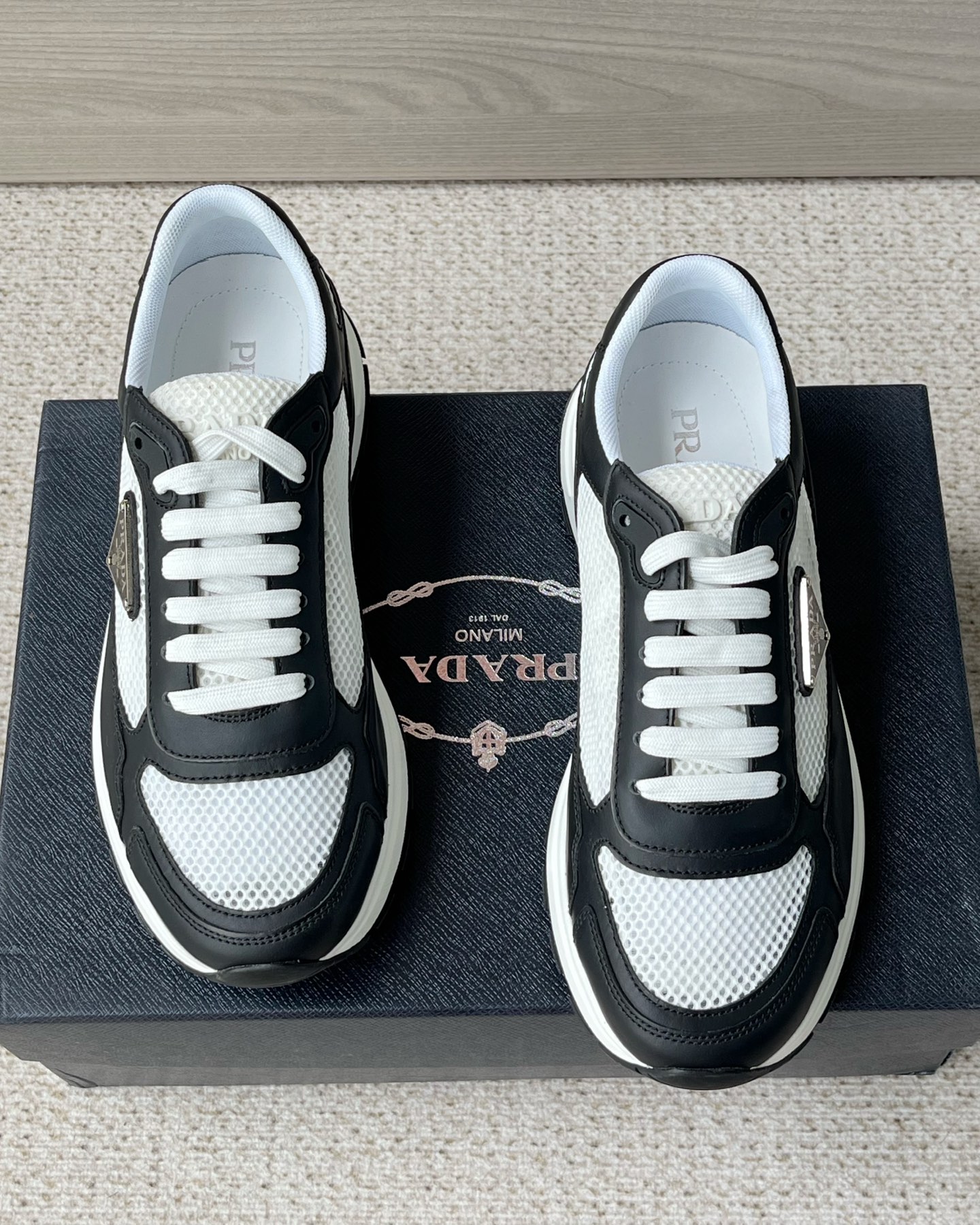 NO:833479,The new Prada Prax men's series casual sneakers. The design of this sneaker is inspired by the 1990s style, using contemporary lines and details to reinterpret the classic sports style. Made of smooth calf leather and nylon fabric mesh upper, it is lightweight, breathable, practical and versatile. It is decorated with an enameled triangle logo on the outside and Prada on the tongue.  Milano rubber label, with 4cm lightweight convex widened rubber sole, breathable fabric lining, and brand logo cowhide feet to create a comfortable wearing experience. Comes with a full set of original packaging dust bag!  Size 39-40-41-42-43-44 standard leather shoe size, prada, prada, sneakers, cowhide19860909新款Prada普拉达 Prax男士系列休闲运动鞋 这款运动鞋的设计灵感源自1990年代款式,运用当代风格线条与细节重新演绎经典的运动风格.采用光滑小牛皮革和尼龙织物网眼鞋面,轻便透气,实用百搭,外侧饰以涂珐琅三角形徽标,鞋舌饰以Prada Milano胶标,搭配4cm轻便的凸纹加宽橡胶鞋底,织物透气内里,品牌徽标牛皮垫脚,缔造舒适的穿着体验.配全套原包装防尘袋！ 码数39-40-41-42-43-44 标准皮鞋尺码,,prada,prada,sneakers,cowhide,Men's shoes