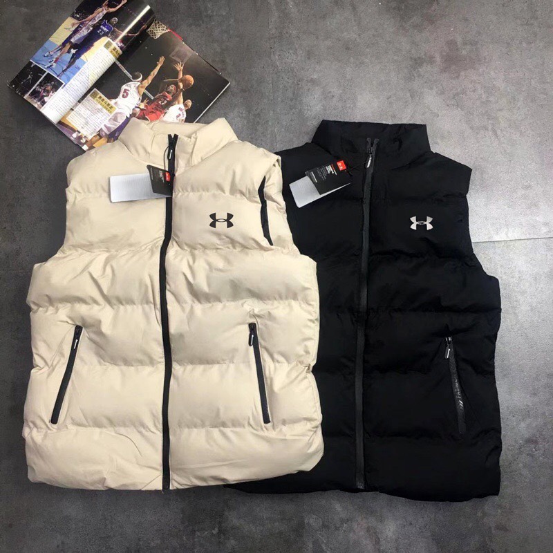 供货价:55💰『官网羽绒棉马甲』百搭不腻版,满足各种身材中空棉,原包装+原吊牌 ,UA安德玛秋冬季立领情侣蓬松棉马甲 外套
经典著作，日常休闲 随意搭配 都是无可挑剔，送人自留！都非常有面A9901
        经典款式 百搭而不会过时，款型简约而不简单，对于各种年龄段男士都能接受。立体修身裁剪，版型更加复合国人身材标准，
精湛工艺打造，走线平稳整齐版本，为凸显上身立体效果，采用V字型绗缝?直线绗缝，胸前印染LOGO，反光 醒目不张扬，低调有格调。
     采优填充 非常严格筛选加工的，蓬松度也非常好！一分不多一分不少！上身有型！不会显得臃肿。两侧口袋拉链闭合 门禁拉链 上身舒适度超高！
面料：绵纶  防水
颜色:  黑色  米色 版型偏小码看尺寸选号
尺码：L~5xl