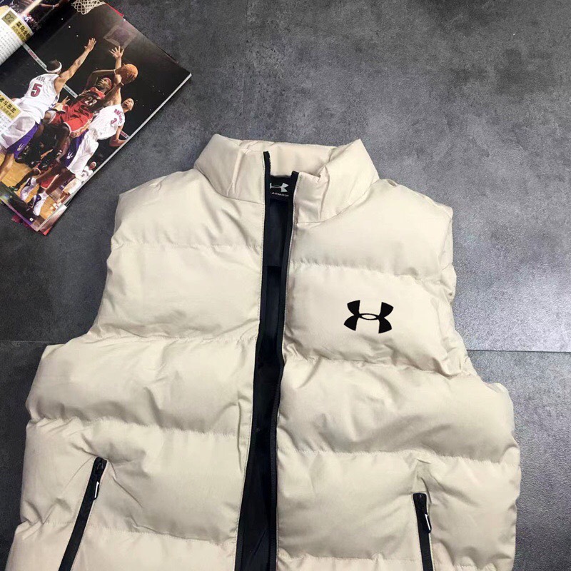供货价:55💰『官网羽绒棉马甲』百搭不腻版,满足各种身材中空棉,原包装+原吊牌 ,UA安德玛秋冬季立领情侣蓬松棉马甲 外套
经典著作，日常休闲 随意搭配 都是无可挑剔，送人自留！都非常有面A9901
        经典款式 百搭而不会过时，款型简约而不简单，对于各种年龄段男士都能接受。立体修身裁剪，版型更加复合国人身材标准，
精湛工艺打造，走线平稳整齐版本，为凸显上身立体效果，采用V字型绗缝?直线绗缝，胸前印染LOGO，反光 醒目不张扬，低调有格调。
     采优填充 非常严格筛选加工的，蓬松度也非常好！一分不多一分不少！上身有型！不会显得臃肿。两侧口袋拉链闭合 门禁拉链 上身舒适度超高！
面料：绵纶  防水
颜色:  黑色  米色 版型偏小码看尺寸选号
尺码：L~5xl