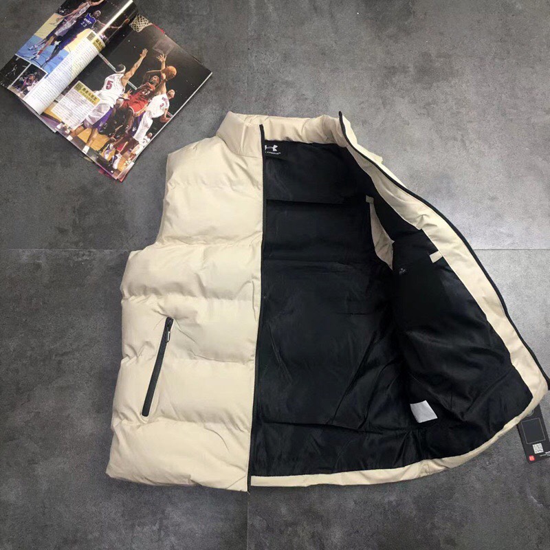 供货价:55💰『官网羽绒棉马甲』百搭不腻版,满足各种身材中空棉,原包装+原吊牌 ,UA安德玛秋冬季立领情侣蓬松棉马甲 外套
经典著作，日常休闲 随意搭配 都是无可挑剔，送人自留！都非常有面A9901
        经典款式 百搭而不会过时，款型简约而不简单，对于各种年龄段男士都能接受。立体修身裁剪，版型更加复合国人身材标准，
精湛工艺打造，走线平稳整齐版本，为凸显上身立体效果，采用V字型绗缝?直线绗缝，胸前印染LOGO，反光 醒目不张扬，低调有格调。
     采优填充 非常严格筛选加工的，蓬松度也非常好！一分不多一分不少！上身有型！不会显得臃肿。两侧口袋拉链闭合 门禁拉链 上身舒适度超高！
面料：绵纶  防水
颜色:  黑色  米色 版型偏小码看尺寸选号
尺码：L~5xl