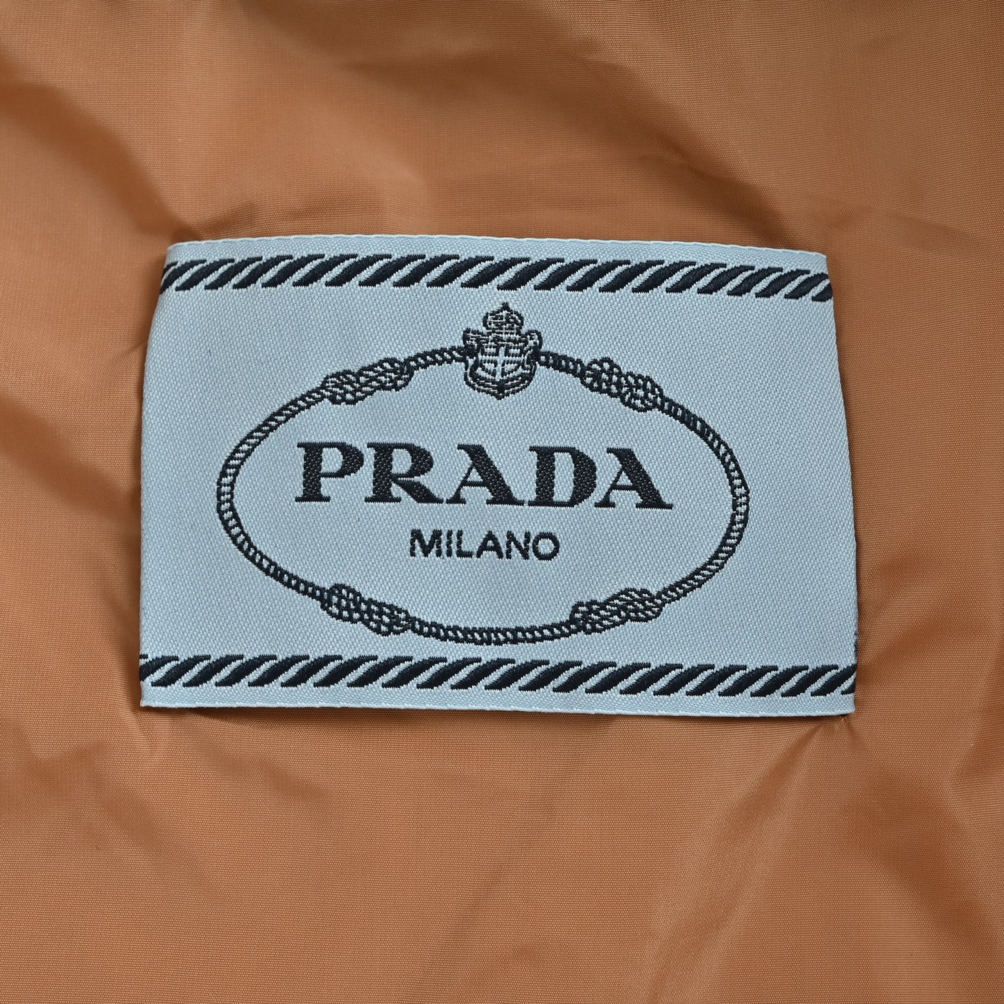 本地自取: 💰550
Prada/普拉达 尼龙拉链口袋撞色立领羽绒服
选用100%锦纶制成的再生尼龙面料,通过先进的纺织技术,编织成紧密且坚韧的布料,提升骨架强度有效阻挡冷风侵袭,锁住羽绒层产生的暖空气,经过紧密的编织工艺和特殊处理之后使其具备防水防风等功能,表面形成一定的荷叶效应,同时抗皱不易变形,易于日常打理。
内衬采用了100%聚酰胺编织而成的焦糖棕色尼龙面料,翻折时形成强烈色彩对冲,宛如将落日熔金注入深邃夜空。聚酰胺纤维以其极高的强度与卓越的亲肤感著称,触感如丝般顺滑,避免了穿着厚重内衣时可能产生的摩擦不适。它与外层尼龙协同工作,共同构建了一个透气、锁温、且极度舒适的微气候环境,让温暖呵护时刻在线,却毫无闷热与束缚感
选用90白鸭绒,蓬松度达220g,确保保暖性能卓越。绒子经过严格筛选与处理之后,不易钻绒。6公分加高立领剪裁,贴合颈部线条却不压迫,,寒风中宛如“第二层肌肤”般温暖。领口与拉链衔接处采用斜角拼接工艺,避免传统立领的呆板感,转头时更显灵动。下摆内置双侧金属调节扣,轻轻下拉即可收紧腰线,上提则恢复宽松廓形——通勤时利落修身,户外时自由无拘。调节扣金属表面经PVD镀层处理,耐磨抗腐蚀,历久弥新。
采用电脑绗缝机,将面料分割为8个独立绒格,针距严格控制在3针/cm,线迹误差不超过0.1mm,缝线选用高强度尼龙线,拉力测试达20N(约2kg承重),杜绝因缝线断裂导致的钻绒问题。
Size:S-XL