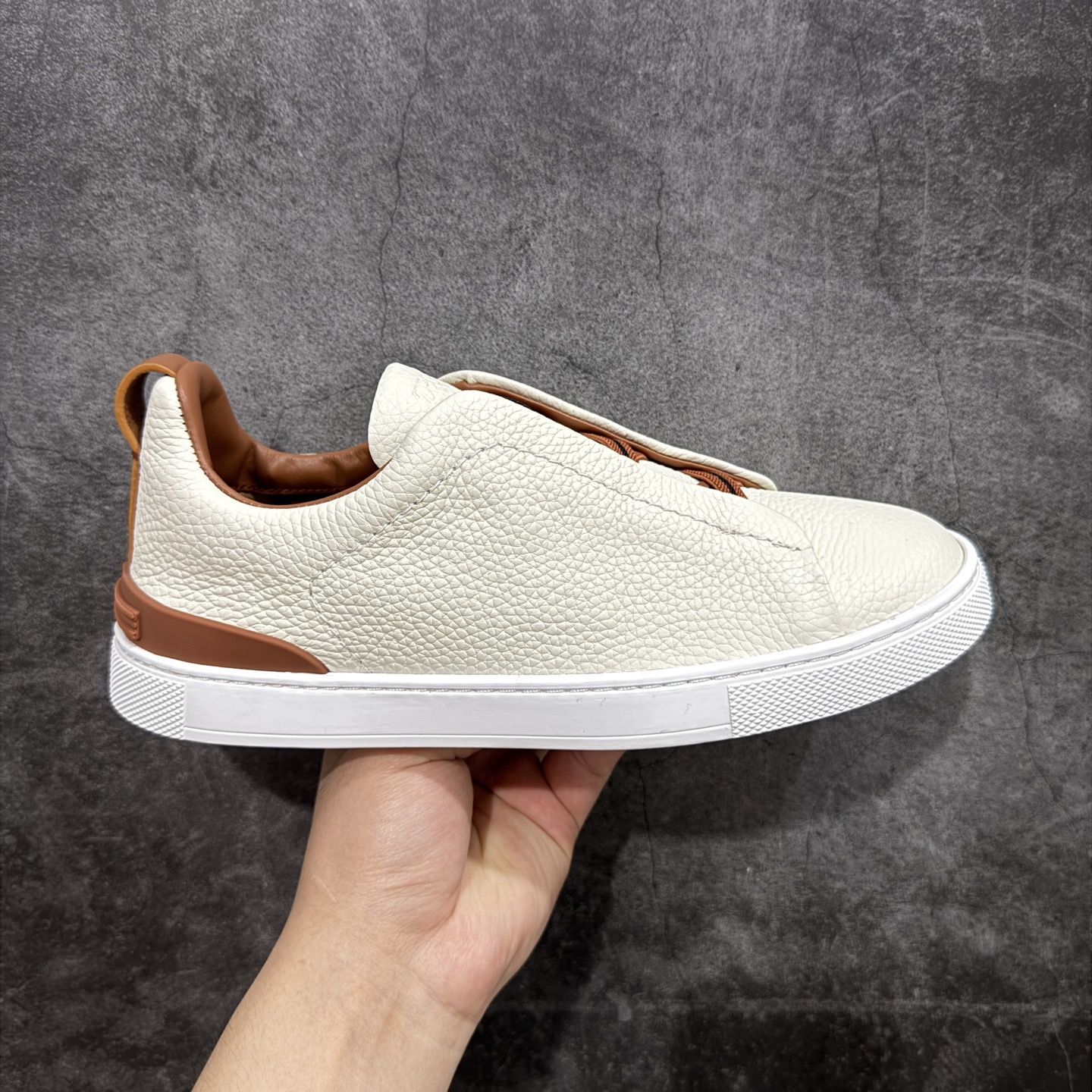 【顶级渠道版】杰尼亚TIZIANO低帮运动鞋 这款Tiziano低帮运动鞋摔花纹牛皮制成，饰以丰富的工艺细节，如骆马红棕色皮革嵌饰和手绘饰边。此优雅材质令这款动感十足的运动鞋转变为精致的休闲单品。耐用的橡胶鞋底可探索城市街道提供所有需的支持。 版型和产品细节：摔花纹牛皮面料，双色宽罗纹针织鞋带满足不同场合搭配不同风格，小牛皮内裡，鞋垫。内底、徽标压纹皮革中底，高弹力记忆鞋垫和超轻橡胶人字纹防滑鞋底，穿着舒服不凡。鞋底周圈加车大底边线。显得匠心十足。 尺码：3940414243444546-选品中心