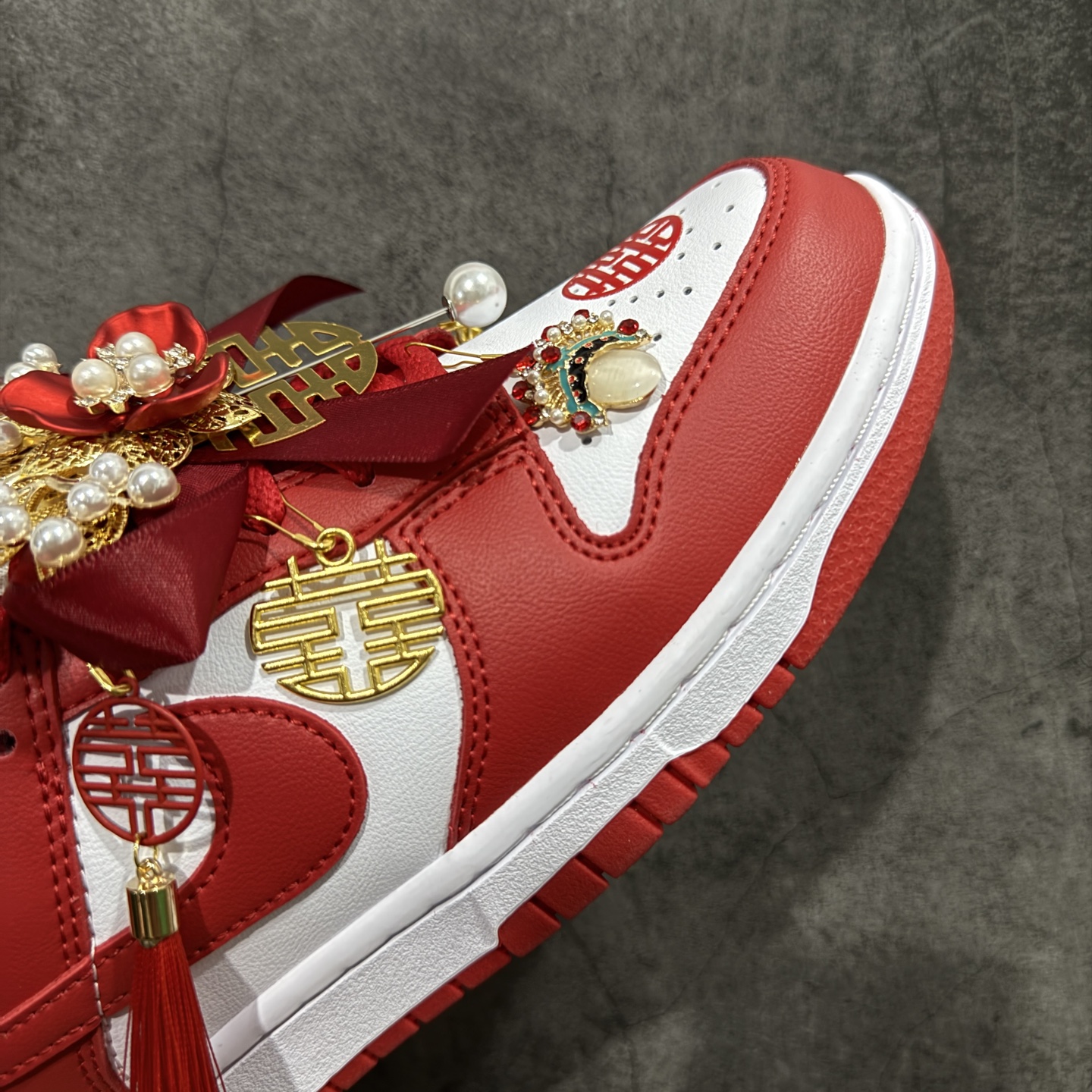 图片[6]-【纯原礼盒版本】NK Dunk Low 低帮婚鞋 锦绣良缘 货号：CU1727-100 该定制版球鞋选用原鞋款为Dunk SB系列球鞋，灵感来自中式婚庆，保留原鞋灰白红基调的基础上，叠加红色丝绒鞋带、增加整体的质感。配饰有双喜金属小挂件，再次呼应主题，呈现出中式婚礼的喜庆、庄重、雅致！鞋面金属挂件及鞋头喜字均可拆卸，同时满足婚庆和日常穿搭需求。本产品所有图片均为实物拍摄，受环境、设备影响会存在微小的色彩差异。定制球鞋均为纯手工定制，满足日常穿戴需求，穿着过程尽量避免剧烈运动和锐物划伤、避免使用高浓度的有机溶剂进行擦洗。 尺码：35.5 36 36.5 37.5 38 38.5 39 40 40.5 41 42 42.5 43 44 44.5 45 46-选品中心