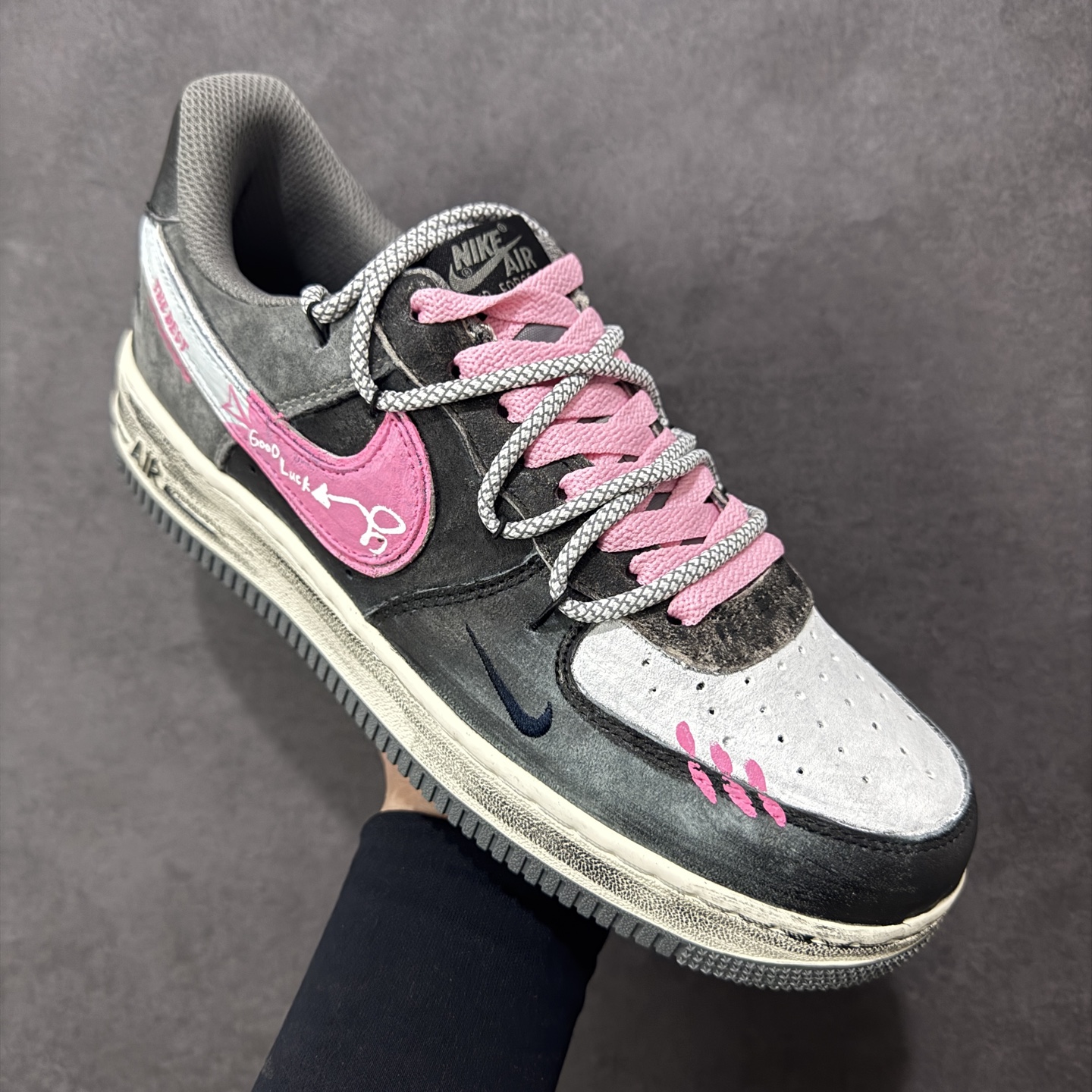 图片[3]-【定制版】手绘涂鸦“灰粉幸运符”Nike Air Force 1 “ Gray-Pink Lucky Charm”空军一号定制板鞋 以 “灰粉撞色 + 幸运元素” 为核心设计：鞋身采用做旧灰调麂皮，搭配亮眼的粉色装饰 —— 鞋侧 Swoosh 印着 “Good Luck” 字样与箭头符号，鞋头点缀粉色缝线肌理，麻绳鞋带混编粉色绳结，强化了随性又俏皮的风格；外底保留经典 “AIR” 标识，做旧磨损的细节让鞋款自带复古氛围感。既延续了空军一号的舒适脚感 货号：YD2425-880 尺码： 36 36.5 37.5 38 38.5 39 40 40.5 41 42 42.5 43 44 44.5 45 编码：HXSA310320-选品中心