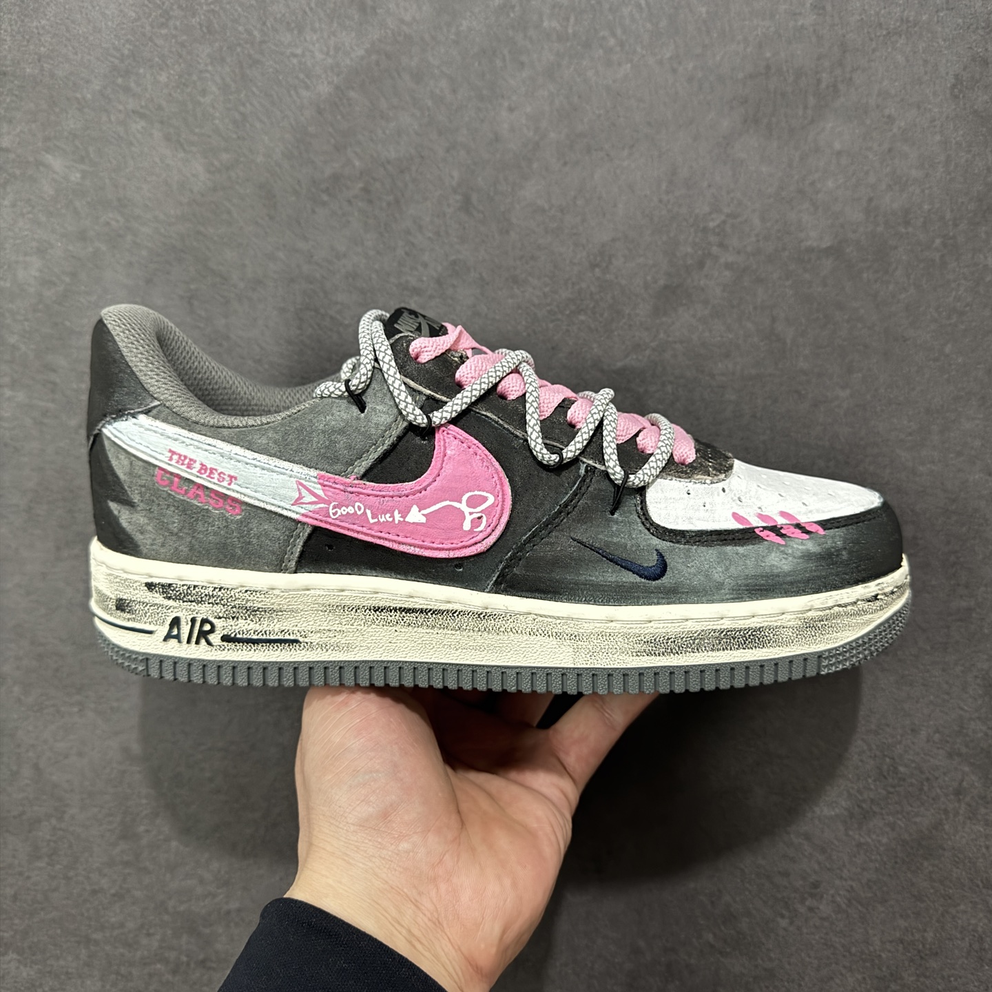 【定制版】手绘涂鸦“灰粉幸运符”Nike Air Force 1 “ Gray-Pink Lucky Charm”空军一号定制板鞋 以 “灰粉撞色 + 幸运元素” 为核心设计：鞋身采用做旧灰调麂皮，搭配亮眼的粉色装饰 —— 鞋侧 Swoosh 印着 “Good Luck” 字样与箭头符号，鞋头点缀粉色缝线肌理，麻绳鞋带混编粉色绳结，强化了随性又俏皮的风格；外底保留经典 “AIR” 标识，做旧磨损的细节让鞋款自带复古氛围感。既延续了空军一号的舒适脚感 货号：YD2425-880 尺码： 36 36.5 37.5 38 38.5 39 40 40.5 41 42 42.5 43 44 44.5 45 编码：HXSA310320-选品中心