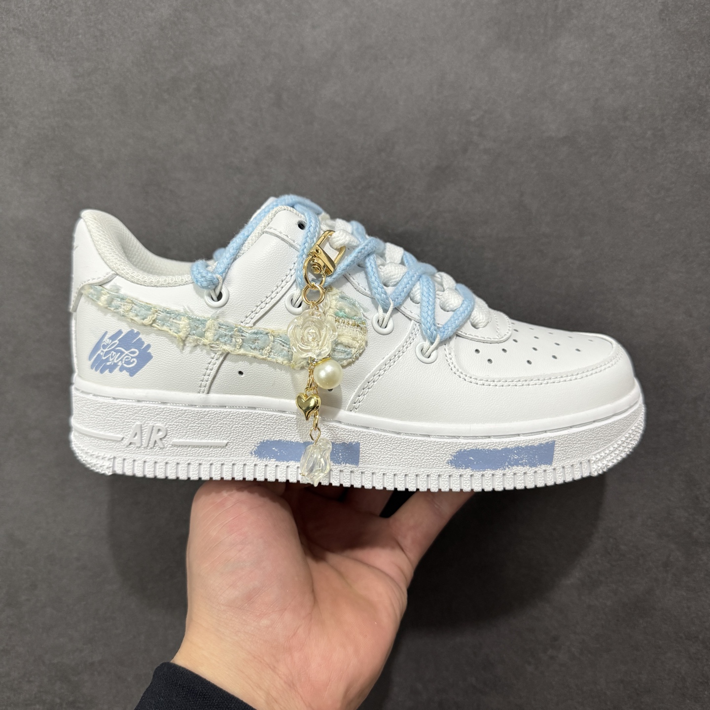 【定制版】“奶蓝编织”✨订制空军一号板鞋 该定制版球鞋选用原鞋款为Nike Air Force 1\'07空军一号，：以纯净白为底色，搭配柔和的浅海盐蓝鞋带，鞋侧Swoosh区域采用编织纹理面料拼接，增添了肌理感与手工定制的独特性。鞋身挂有珍珠、水晶吊坠等精致配饰，与浅蓝鞋带、编织元素呼应，打造出甜美元气的少女风格；鞋身还点缀了同色系的印花/刺绣小元素，让整体设计更有层次感。 货号：DC9999-223 尺码： 36 36.5 37.5 38 38.5 39 40 40.5 41 42 42.5 43 44 44.5 45 编码：HXSA310320-选品中心