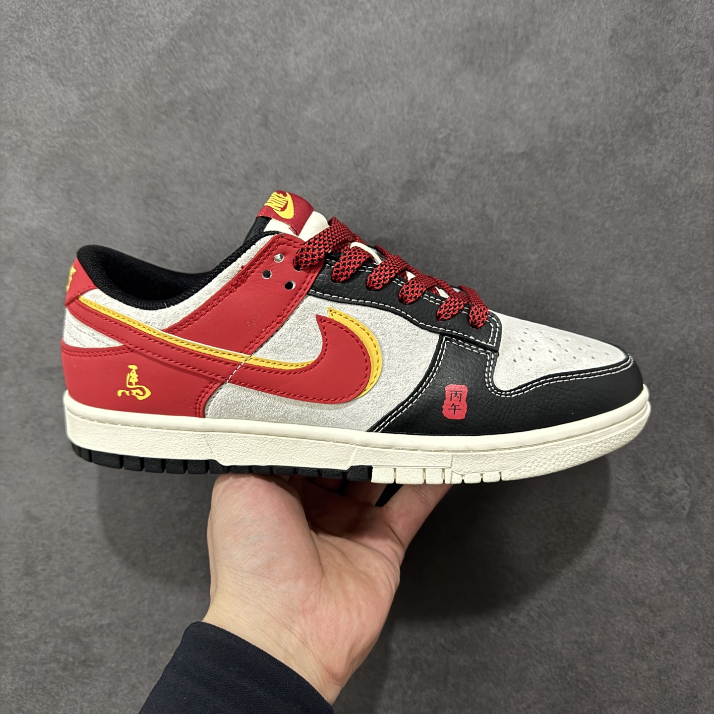 【定制版】红黑生肖， Dunk年味拉满 Nike Dunk Low CX5050-Y63以马年生肖为灵感，把国风年味和街头经典狠狠融合，直接成为新年鞋柜的C位选手🐎鞋身以白黑红为主调，经典的Dunk Low轮廓搭配质感皮质，红色Swoosh边缘缀着金黄线条，瞬间勾勒出新年的喜庆氛围。鞋侧的“马”字书法刺绣、鞋头的国风印章细节，将生肖文化与潮流设计完美碰撞，做旧质感的米白中底搭配黑色外底，复古又不失腔调。不管是新年穿搭的点睛之笔，还是日常街头的个性表达，这双鞋都能轻松hold住。既是Dunk系列的经典延续，也是国风潮流的全新演绎，新年想穿出不一样的街头年味，这双生肖Dunk绝对是不二之选！ 尺码：36 36.5 37.5 38 38.5 39 40 40.5 41 42 42.5 43 44 44.5 45 编码：GLB320330-选品中心