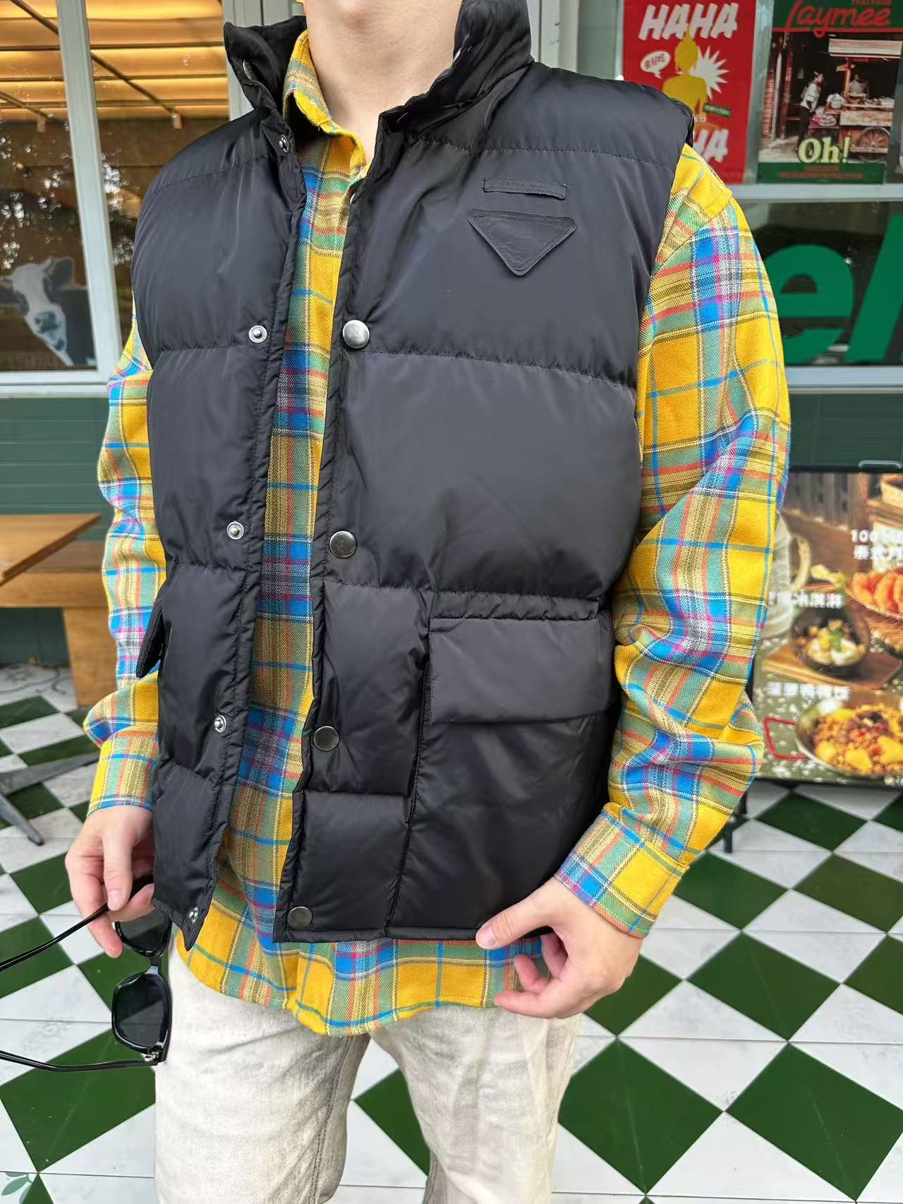 NO:528127,Down jacket -.PRADA triangular down vest selection of front fabric. The brand's signature recycled nylon fabric is selected. It has high strength, tear resistance, wear resistance and other characteristics. Its texture is light and waterproof, and is suitable for multiple scenarios. Its wrinkle and quick drying characteristics are also easy to maintain and maintain daily. Process: The felt cloth material is flatly fixed on the stamping machine. Under the control of the ground, the upper die is driven down at extremely high speed and pressure. The sharp edge is cut off the felt cloth fibers in an instant like a paper cutter. The whole process is completed in milliseconds. The triangle mark shape without burrs and brushes at the edge is formed through precise calculations. High-quality filler: 90 white duck down is selected, with a weight of 160g, ensuring excellent warmth performance. After strict screening and processing of the velvet, it is not easy to drill velvet, ensuring durability  Comparison of accessories for custom-made breast marks, comparison of custom-made snaps, comparison of custom-made three marks SIZE:46 48 50 52,,prada,down jacket,alexander wang19860909羽绒服-.PRADA饰织物三角标羽绒马甲 正面面料选择 选用品牌标志性的再生尼龙面料,与传统尼龙性能相当,具备高强度,抗撕裂,耐磨损等特性.其质地轻盈,同时又具备防水功能适合多场景需求.抗皱,快干的特点也易于日常打理维护. 工艺 将毛毡布材料平整的固定在冲压机台上,在地懊恼控制下,驱动上模以极高的速度和压力向下运动,锋利的刃口在压力下,像裁纸刀一样瞬间干净的切断毛毡布纤维,整个过程在毫秒内完成.通过精确的计算形成边缘无毛刺和拉丝的三角标形状. 高品质填充物 选用90白鸭绒,克重达160g,确保保暖性能卓越.绒子经过严格筛选与处理之后,不易钻绒,保证了耐用性 辅料一比一定制胸标 一比一定制按扣 一比一定制三标 SIZE:46 48 50 52,,prada,down jacket,alexander wang,Men's clothing