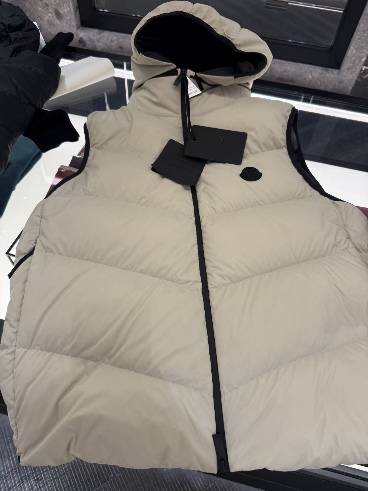 羽绒服-。MONCLER饰章连帽羽绒马甲面料选择：选用100%锦纶制成的尼龙面料，通过先进的纺织技术，编