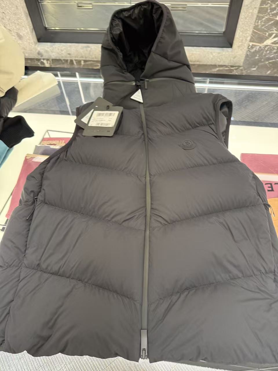 羽绒服-。MONCLER饰章连帽羽绒马甲面料选择：选用100%锦纶制成的尼龙面料，通过先进的纺织技术，编