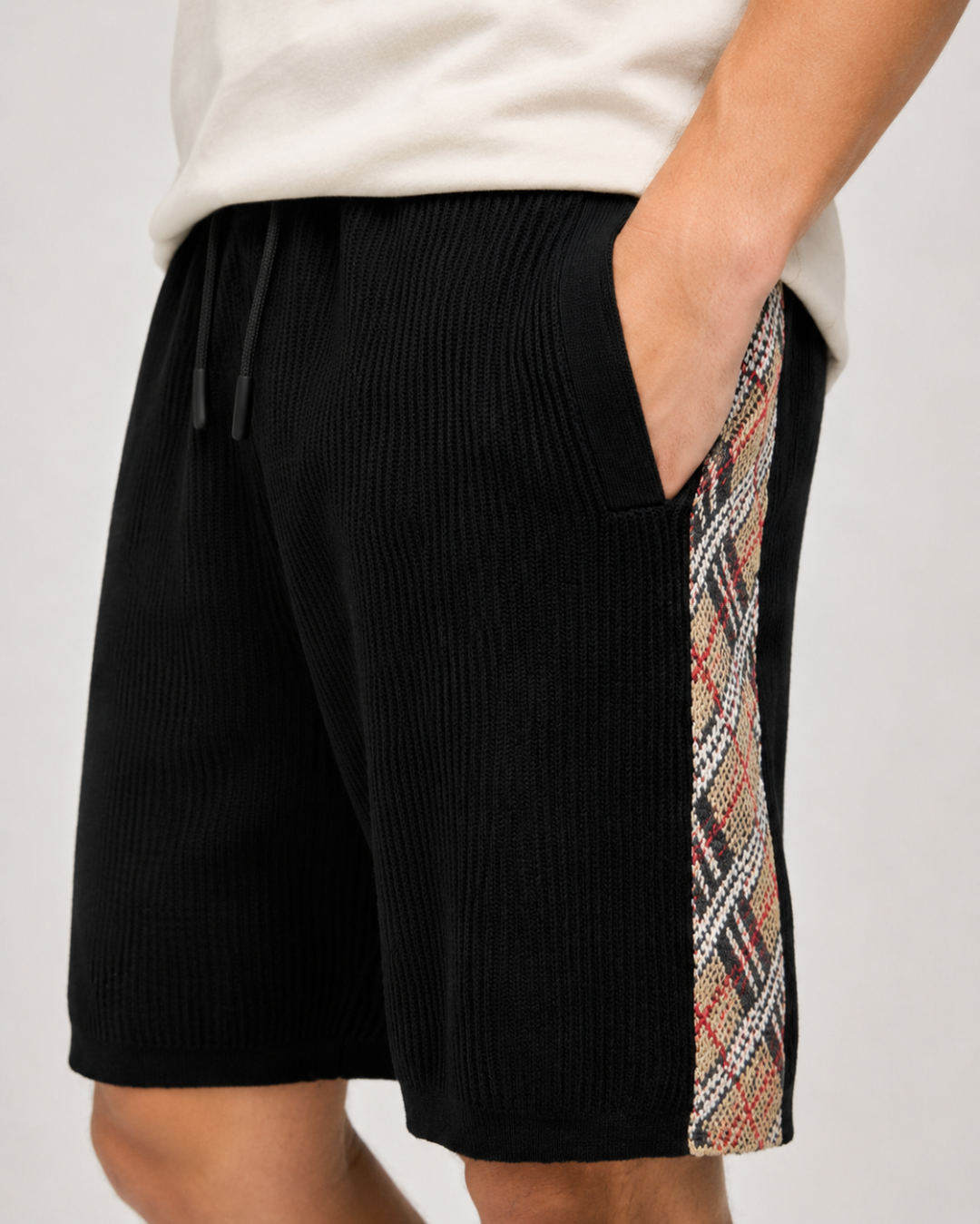 NO:916567,.Bur plaid decorative knitted shorts fabric weaving. The main body is made of high-count lightweight cotton yarn, using the vertical pit rib knitting process. The yarn is plied and shaped, and is woven into a three-dimensional vertical grain texture through a circular knitting machine. The special weaving method forms an air layer inside the fabric, which is soft and not heavy to the touch, taking into account both breathability and drape. The fabric texture is uniform and regular, not easy to deform and wrinkle, and the pit strips remain clear and three-dimensional after multiple washings, making it comfortable and unconstrained to wear next to the body.  Details: Vintage plaid knitted webbing is spliced on both sides of the trousers, using synchronous jacquard knitting technology. The plaid is woven simultaneously with multi-color yarns, with clean color boundaries and no halo jumpers. The webbing and trouser body panels are precisely sewn and spliced, and the lines are straight and firm. The classic plaid elements break the monotony of pure black fabrics, highlighting the recognition in simplicity. Jacquard technology  The waistband has a widened ribbed one-piece woven structure, with a built-in cotton drawstring, and the rope ends are sealed to prevent loose threads. The waistband is integrated with cursive letter jacquard craftsmanship, and the yarns are woven in layers to form a slightly raised three-dimensional texture and a vague relief effect, which is smooth to the touch but rich in visual layers. Accessories are customized one to one with three labels Size: S M L,, burberry, shorts,19860909.Bur格纹装饰针织短裤  面料织造 主体选用高支轻盈棉质纱线织造,采用竖向坑条罗纹针织工艺,纱线经过合股定型处理,经由大圆机一体织出立体竖纹肌理.特殊织法形成面料内部空气层,触感柔软不厚重,兼顾透气度与垂坠感；布面纹理均匀规整,不易变形起皱,多次水洗后坑条依旧清晰立体,贴身穿着舒适无束缚.  细节 裤身两侧拼接复古格纹针织织带,采用同步提花针织工艺,格纹由多色纱线同步织入,色彩边界干净利落,无晕色跳线.织带与裤身裁片精密车缝拼接,走线平直牢固,经典格纹元素打破纯黑面料单调感,简约中凸显辨识度.  提花工艺 腰头为加宽罗纹一体织结构,内置棉质抽绳,绳头做封胶处理不易散线.腰头处融入草书字母提花工艺,纱线分层织入形成微微凸起的立体纹路、若隐若现的浮雕效果,触感平滑却视觉层次丰富.  辅料一比一定制三标 Size:S M L,,burberry,shorts,,Men's clothing