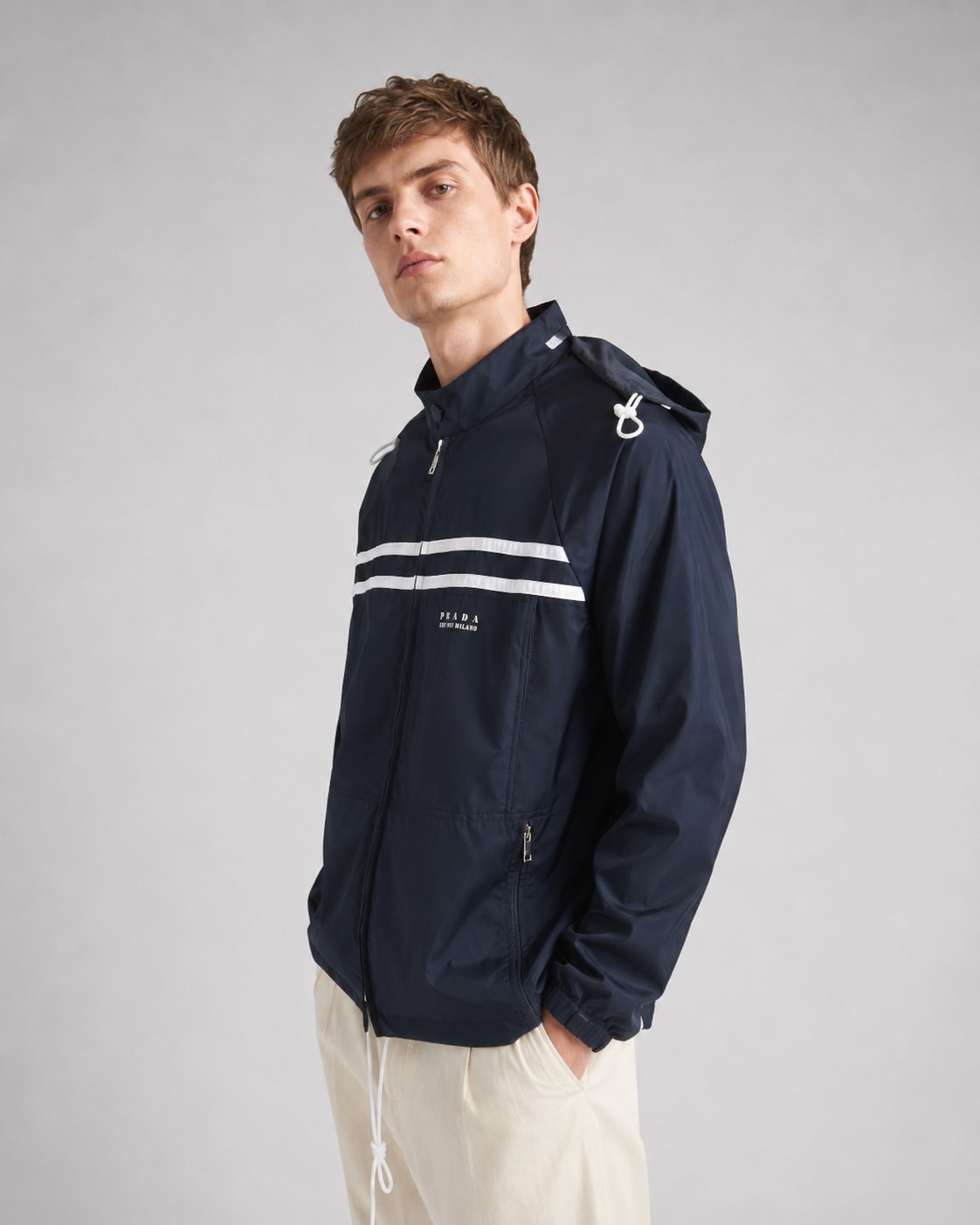 NO:935805,.PRA Regenerated Nylon Printed Logo Jacket Fabric Selection: The brand's iconic regenerated nylon fabric is selected, which has the same performance as traditional nylon. After being treated with an anti-fouling, waterproof and tear-resistant composite process, the surface presents a unique silk luster touch, taking into account high strength, tear resistance, wear resistance and other properties. The overall texture is light, wrinkle-resistant, quick-drying and easy to maintain on a daily basis. Process  The letter logo is decorated on the front piece through the glue printing process. The pressure of the scraper is even. After 5 scraping printings, it is ensured that the printing thickness presents a micro-three-dimensional convex structure, and the glue is fully penetrated and covered. Finally, after curing at high temperature, the pigment is firmly bonded with the fabric and is not easy to fall off due to friction. Details  Unlined single-layer structure, relying on the high-density weaving characteristics of regenerated nylon, making it both breathable and protective. It adopts a stand-up collar structure, which fits the neck line, taking into account windproof function and smart temperament. The detachable hood meets the needs of multiple scenes. Accessories One-to-one placket zipper puller One-to-one pocket zipper puller One-to-one collar label SIZE: S M L XL,, prada, jackets & coats, hats,19860909.PRA再生尼龙印花徽标夹克 面料选择 选用品牌标志性的再生尼龙面料,与传统尼龙性能相当,通过防污防水抗撕裂复合工艺处理之后,表面呈现独特的丝绸光泽触感,兼顾高强度,抗撕裂,耐磨损等特性,整体质地轻盈,抗皱,快干的特点也易于日常打理维护. 工艺 通过胶浆印花工艺在前片处饰以字母徽标,刮刀压力均匀,经过5次刮印确保印花厚度呈现微立体凸起结构,并使胶浆充分渗透并覆盖.最后通过高温固化后,颜料与面料结合牢固,不易因摩擦导致脱落. 细节 无衬里单层结构,依托再生尼龙的高密度编织特性,使其透气性与防护性并存.采用立领结构,贴合颈部线条,兼顾防风功能和干练气质.可拆卸兜帽,满足多场景需求. 辅料一比一开襟拉链头 一比一口袋拉链头 一比一领标 SIZE:S M L XL,,prada,jackets & coats,hats,,Men's clothing