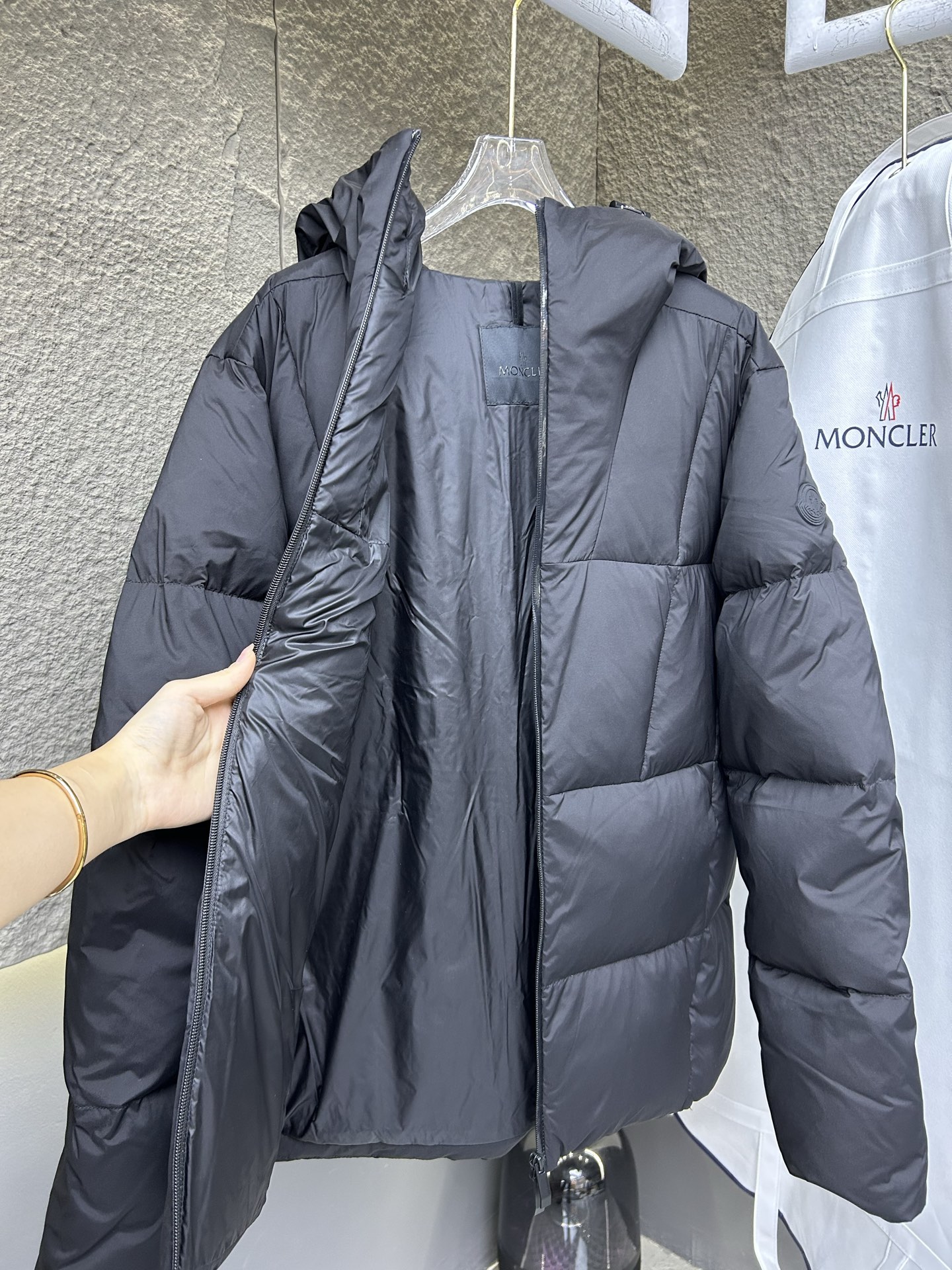 Moncler Fusain short down jacket inspired by racing. Features quilted nylon, lightweight warmth, sleek silhouette, hood, and reflective zipper. Available in black and off-white.-Big cat