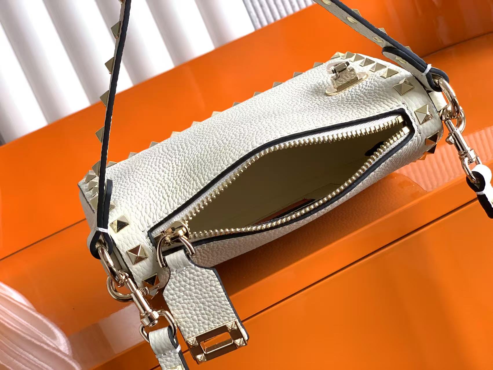 🆕 Garavani Rockstud 小号粒面小牛皮斜挎包,标志性的钩扣开合设计经重新诠释，止挡拉链拉