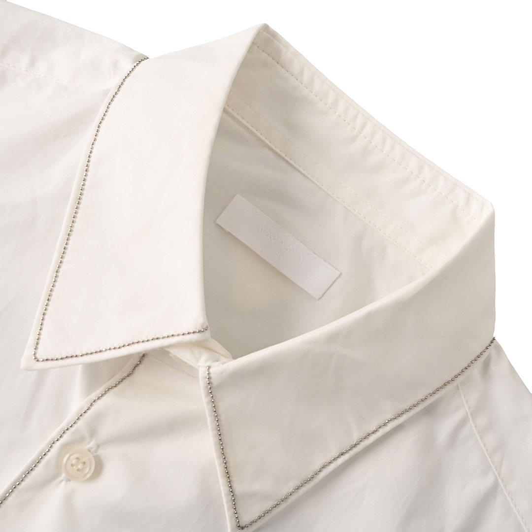 正品级💰330 Prada普拉达PRD 银边镶珠长袖衬衫 独家款！链形针迹刺绣报废率极高 ，衣领、袖口和正面饰链形针迹刺绣宽松廓形，传统衣领，直裁下摆，传统袖口 珍珠母贝钮扣开合，背面织物三角形徽标，从面料舒适度 做工细节，感受与市场货区别。 #因镶珠款式特性，请勿高温、机洗、揉洗！！！因此产生的售后问题不提供售后处理！！ Size：S-XL
