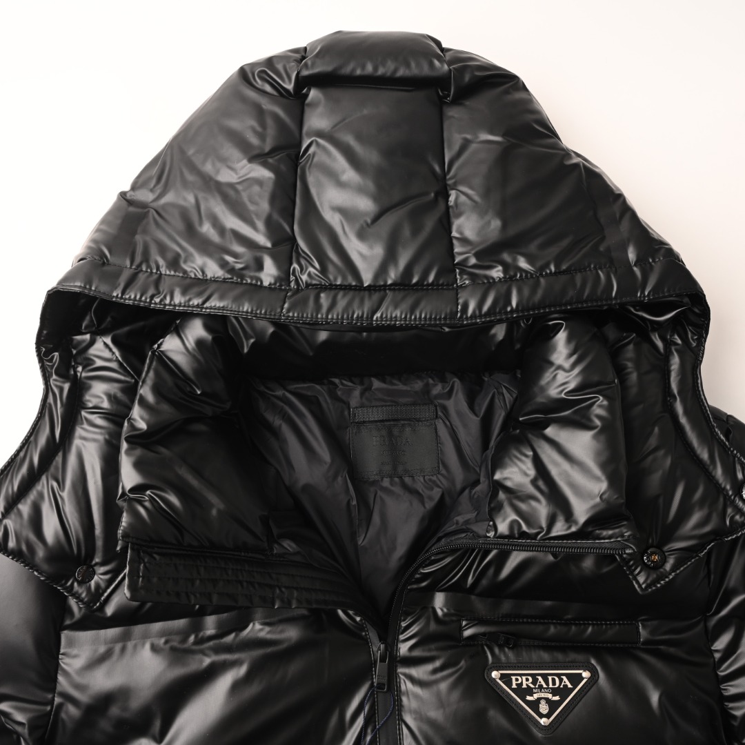 正品级 Prada/普拉达PRD 经典三角标帽子可拆卸羽绒服 此款廓形丰满的羽绒外套采用Linea rossa独特的双层轻质粘合尼龙面料打造，搭配连帽衣领、直裁衣袖和正面拉链拉合，与横向绗缝，元素和下摆弹力束绳共同塑造鲜明廓形，轻质粘合尼龙科技面料具有防风、耐磨、防水和透气等，高科技性能,是一款多功能科技面料，衬里采用精细密实的可再生微纤维面料打造,触感轻盈，柔软，鹅绒和 Graphene加衬有助于调节体温，别具功能性，鸭绒材质赋予加衬填料更加轻盈的特色，提升服装的保温性能 Size: 48-56