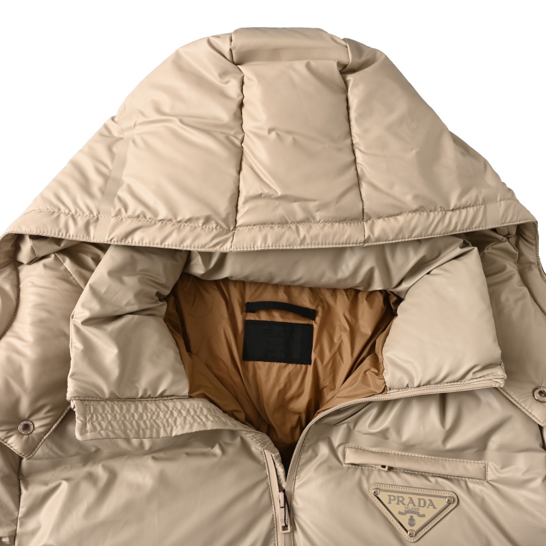 正品级 Prada/普拉达PRD 经典三角标帽子可拆卸羽绒服 此款廓形丰满的羽绒外套采用Linea rossa独特的双层轻质粘合尼龙面料打造，搭配连帽衣领、直裁衣袖和正面拉链拉合，与横向绗缝，元素和下摆弹力束绳共同塑造鲜明廓形，轻质粘合尼龙科技面料具有防风、耐磨、防水和透气等，高科技性能,是一款多功能科技面料，衬里采用精细密实的可再生微纤维面料打造,触感轻盈，柔软，鹅绒和 Graphene加衬有助于调节体温，别具功能性，鸭绒材质赋予加衬填料更加轻盈的特色，提升服装的保温性能 Size: 48-56