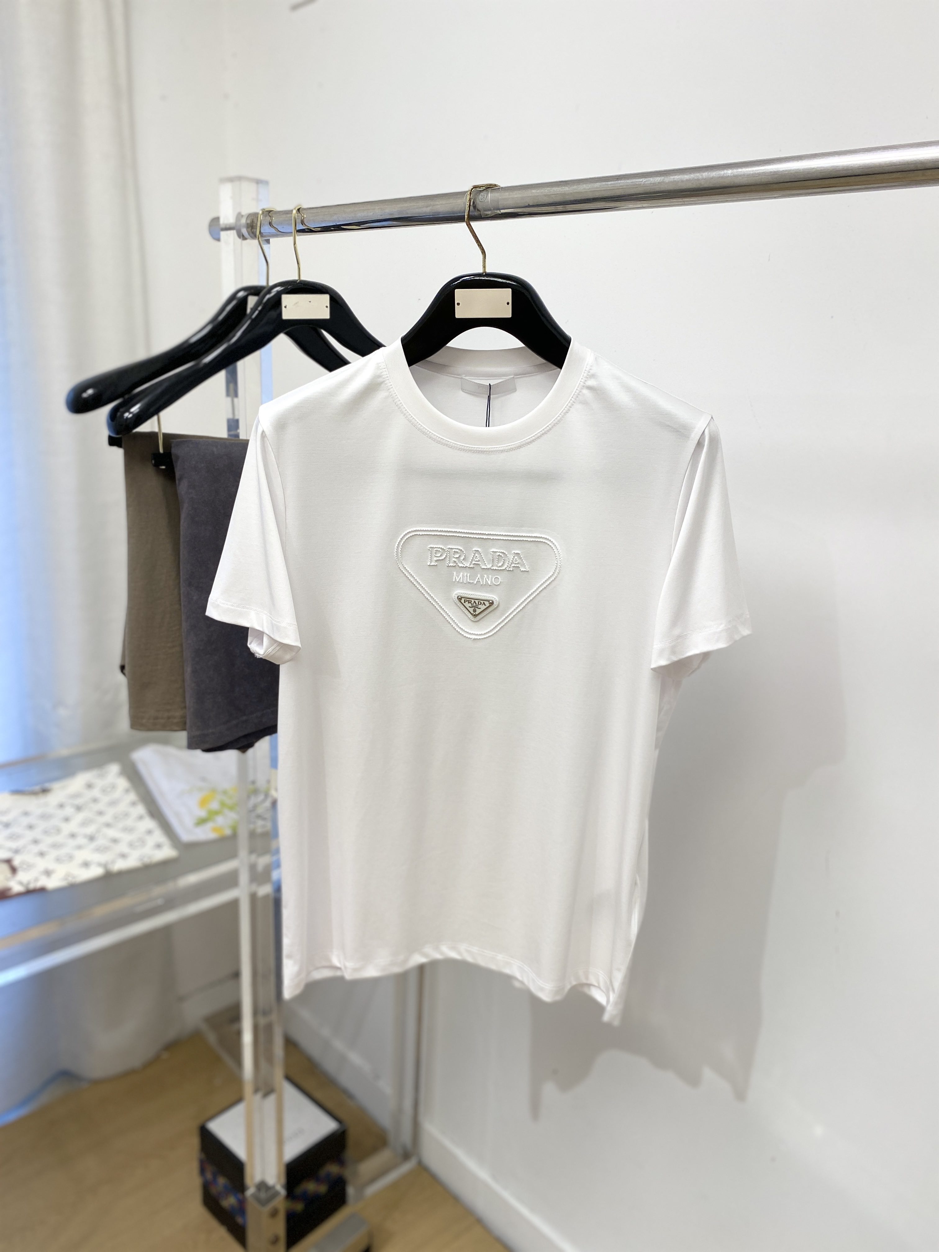 普拉达、2026新品短袖T恤，帅气时尚，简约百搭款。胸前精致刺绣五金装饰图案logo，面料棉 不仅挺括，