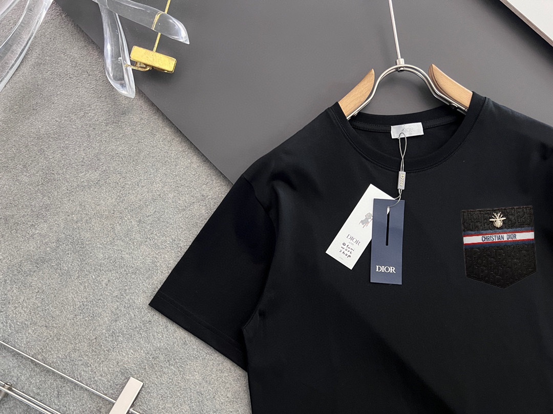 P70，  DIor迪奥
2025早春新款短袖  胸口手工定制logo
纯手工订做金丝线  下摆经典钮扣手缝
官网同步  专柜（百分之百纯棉面料 ） 贴肤舒适
耐看又好穿  原厂工艺一丝不苟
定制280克同缸染面料   手感非常舒服
最新砖柜同步  OS落肩版型  时尚又个性
超级百搭好看的一款  男女都非常合适
人手必备款  吊牌  领标  水洗麦  三标齐全 码数：S-XXL码