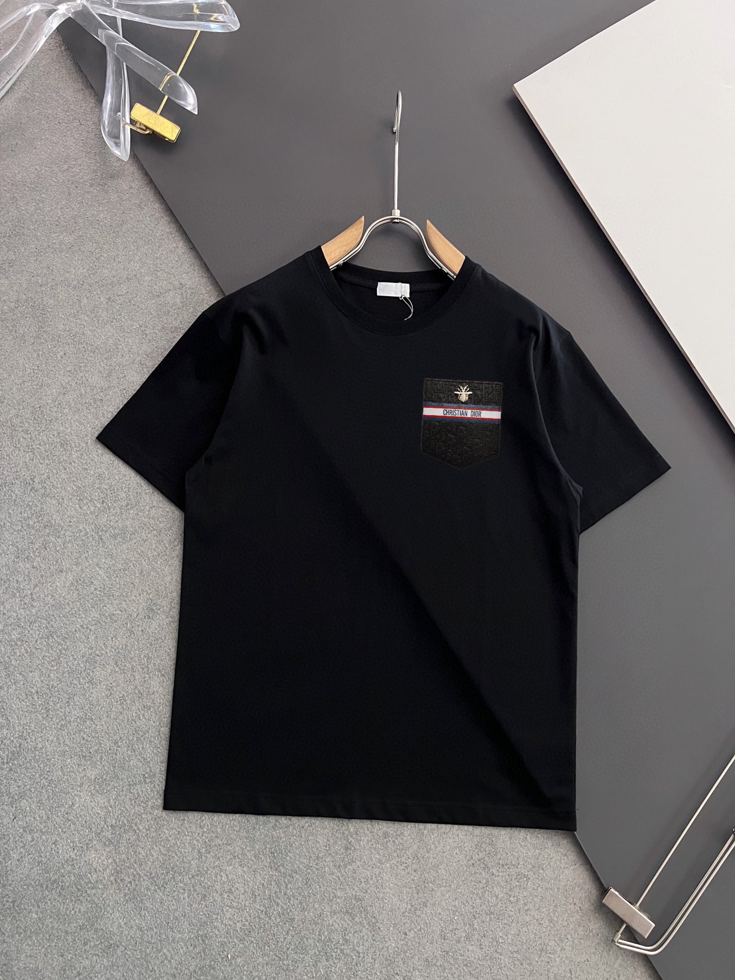 P70，  DIor迪奥
2025早春新款短袖  胸口手工定制logo
纯手工订做金丝线  下摆经典钮扣手缝
官网同步  专柜（百分之百纯棉面料 ） 贴肤舒适
耐看又好穿  原厂工艺一丝不苟
定制280克同缸染面料   手感非常舒服
最新砖柜同步  OS落肩版型  时尚又个性
超级百搭好看的一款  男女都非常合适
人手必备款  吊牌  领标  水洗麦  三标齐全 码数：S-XXL码