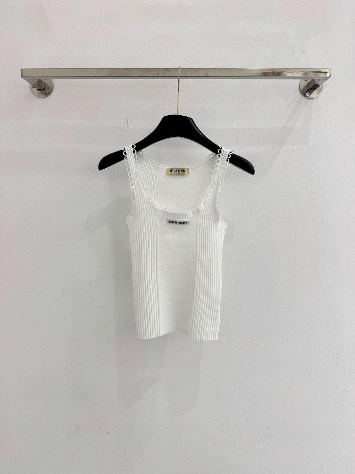 Chanel ‌无袖设计，花边装饰，胸前点缀品牌标志性刺绣标识，面料纹理细腻，整体质感轻盈透气