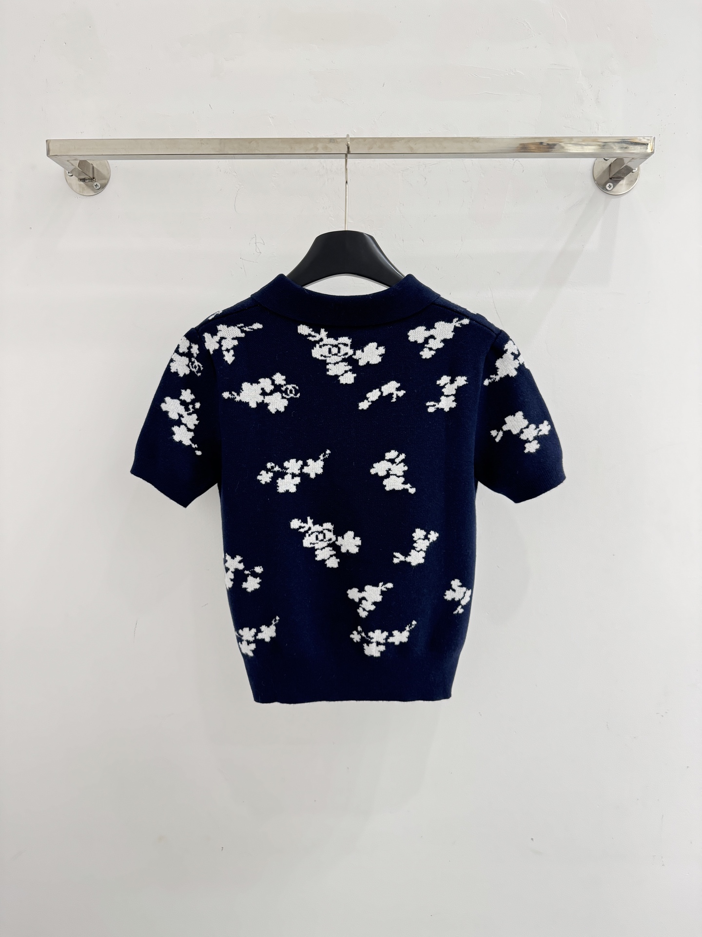 Chanel 短袖针织Polo衫，布满白色花卉图案，领口白色纽扣点缀，提花造型小巧 ，增添自然清新感