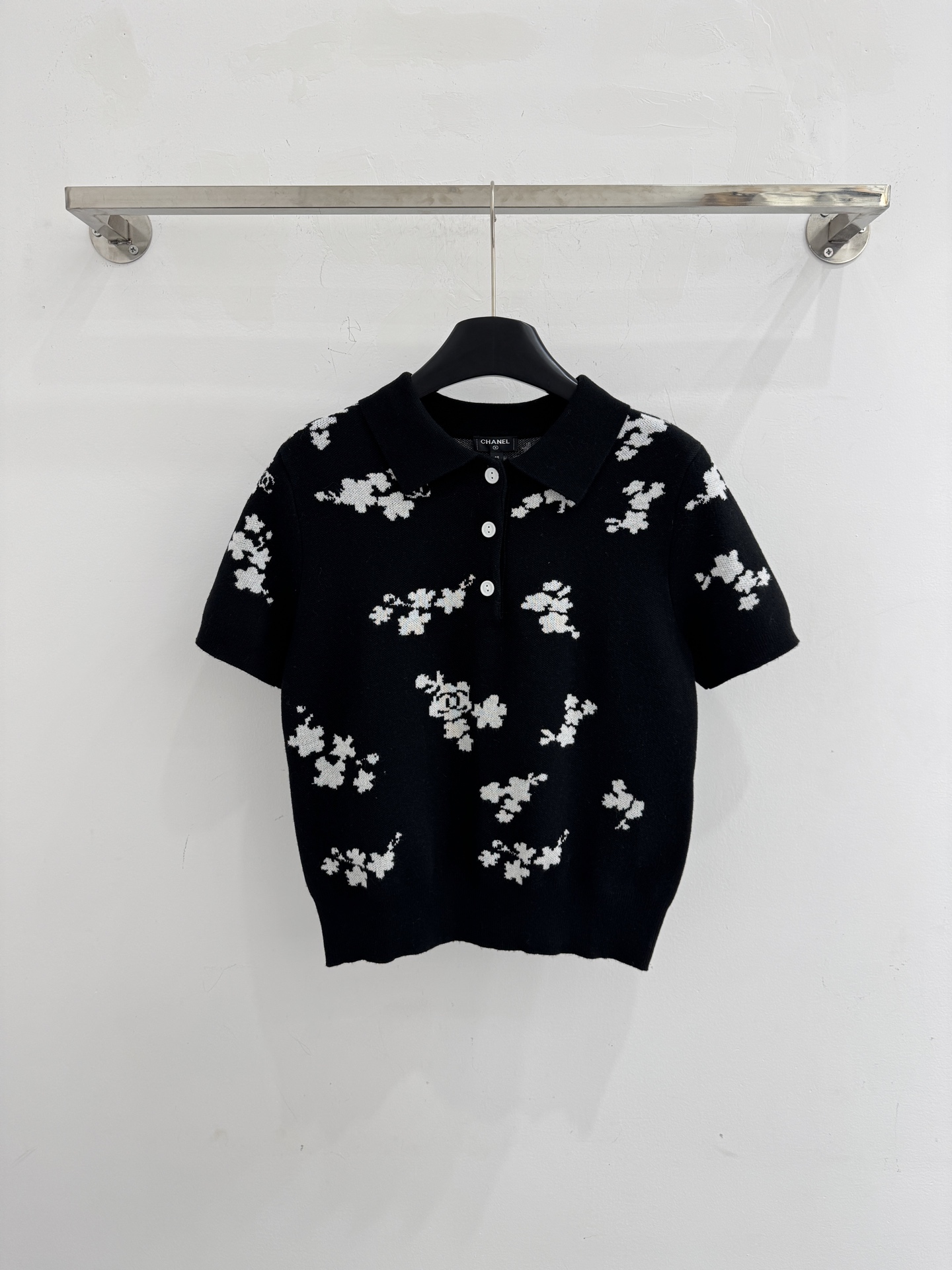 Chanel 短袖针织Polo衫，布满白色花卉图案，领口白色纽扣点缀，提花造型小巧 ，增添自然清新感