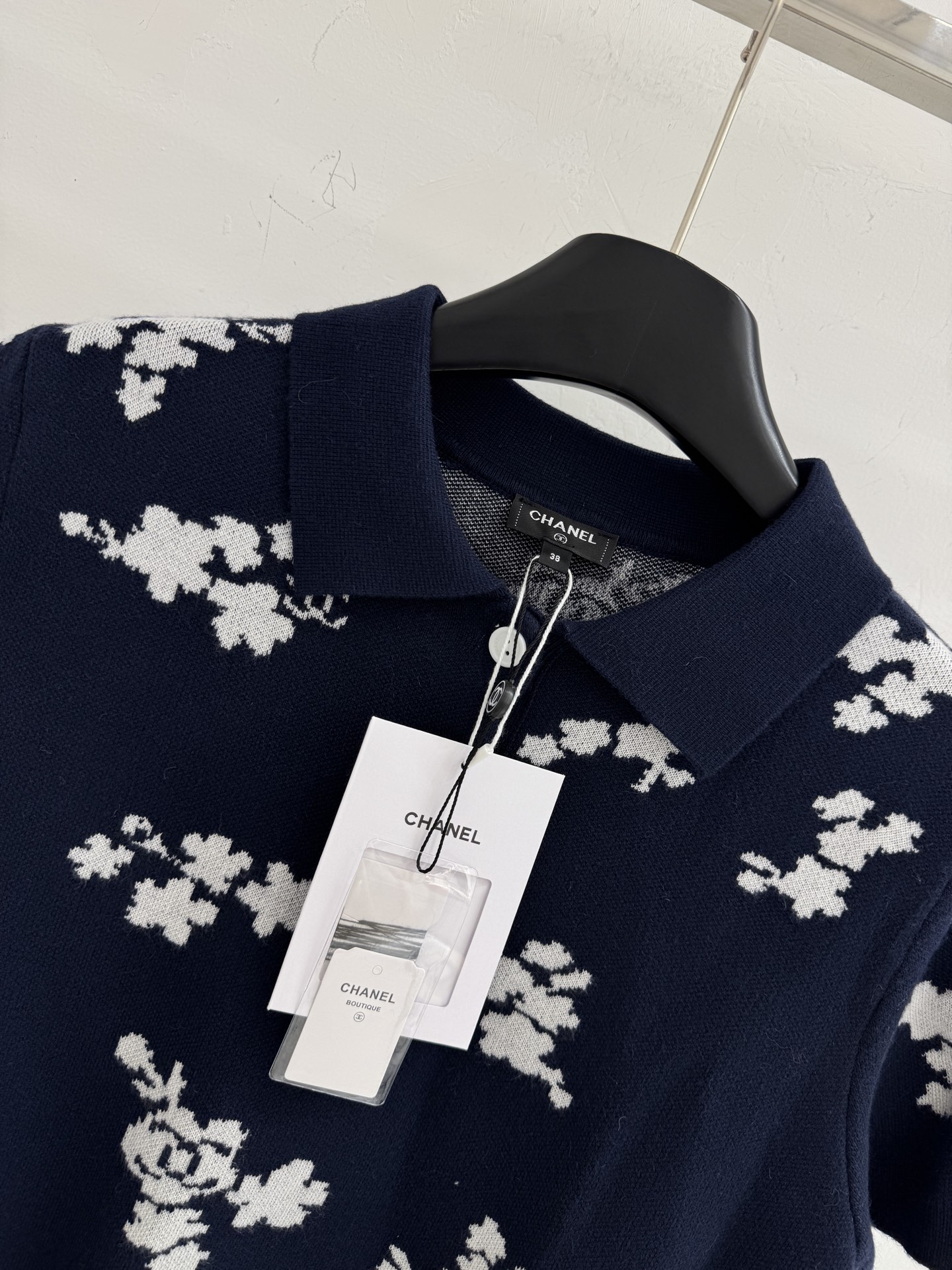 Chanel 短袖针织Polo衫，布满白色花卉图案，领口白色纽扣点缀，提花造型小巧 ，增添自然清新感