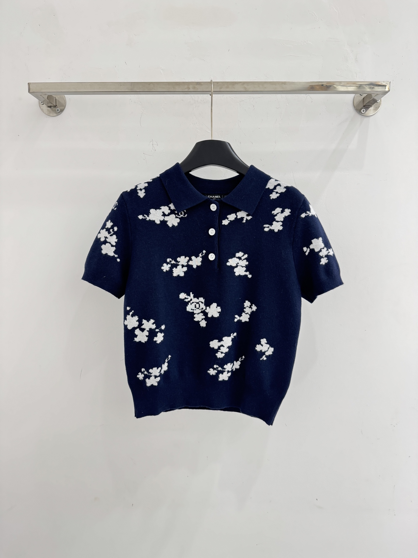 Chanel 短袖针织Polo衫，布满白色花卉图案，领口白色纽扣点缀，提花造型小巧 ，增添自然清新感