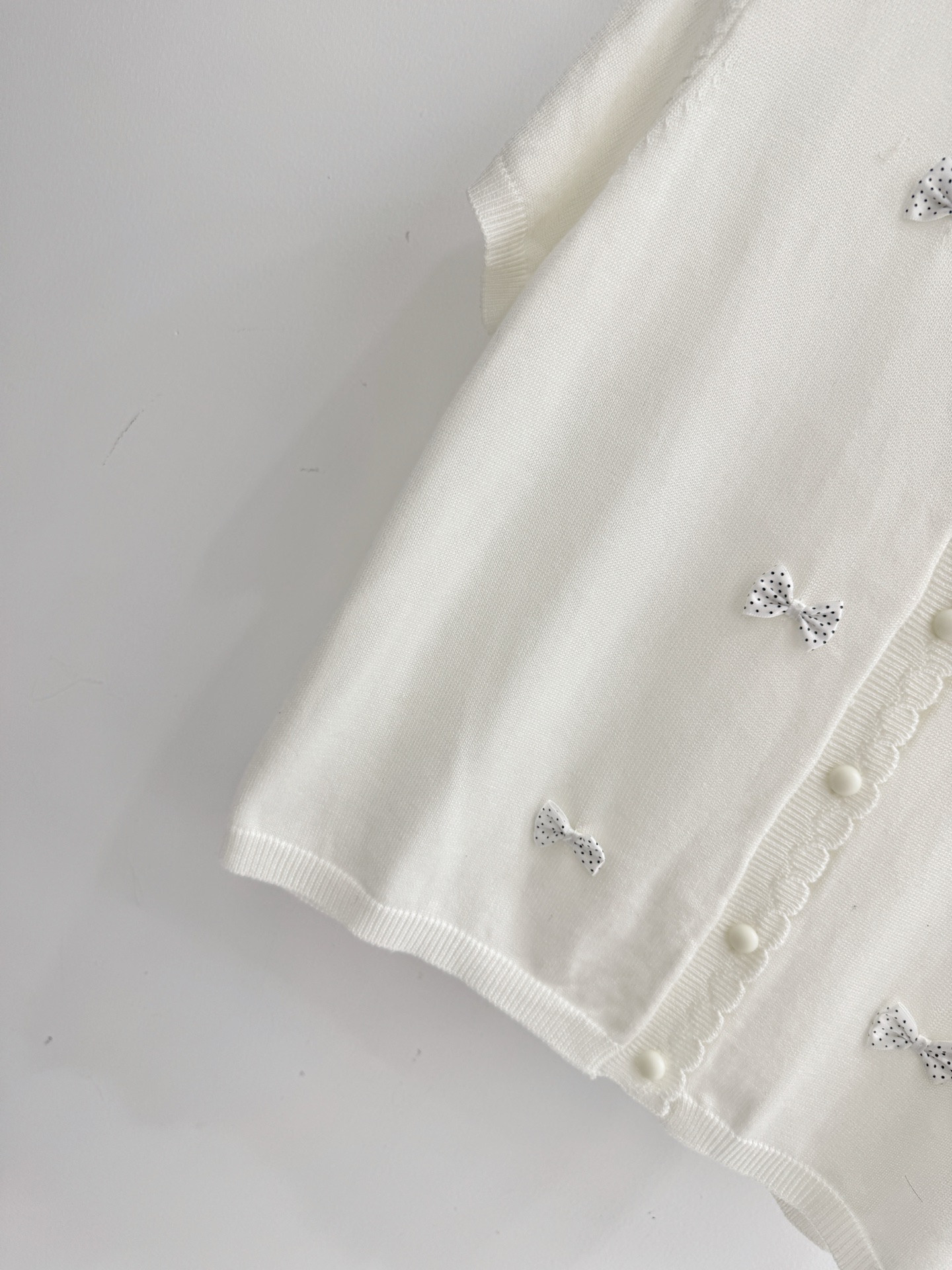 Unknown 白灰两色短袖针织开衫，白色款缀满波点蝴蝶结，搭配波浪边领口与品牌刺绣，甜美减龄，尽显少女感