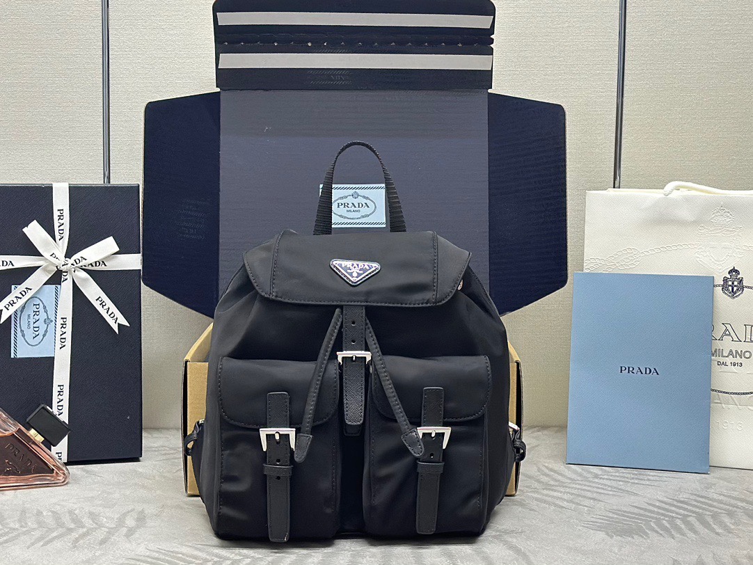 P family  Small Size Backpack 1BZ677 Silver Label. This women's backpack features imported waterproof fabric, top-quality hardware, and adjustable fabric straps. It has a drawstring flap design, two front magnetic snap pockets, and logo lining. Dimensions: 28 x 23.5 x 12 cm. Item number: 007650. image 1