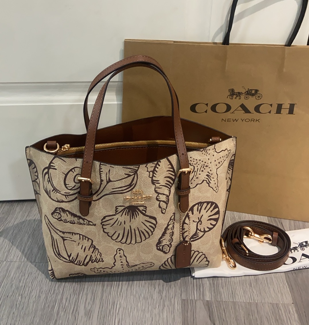 Coach's new CBH63 beach shell print Mollie tote for July features a fresh summer ocean theme with a sandy yellow base color. The bag is adorned with seashells and starfish, and can be carried by hand or worn crossbody, measuring 25 cm. image 1