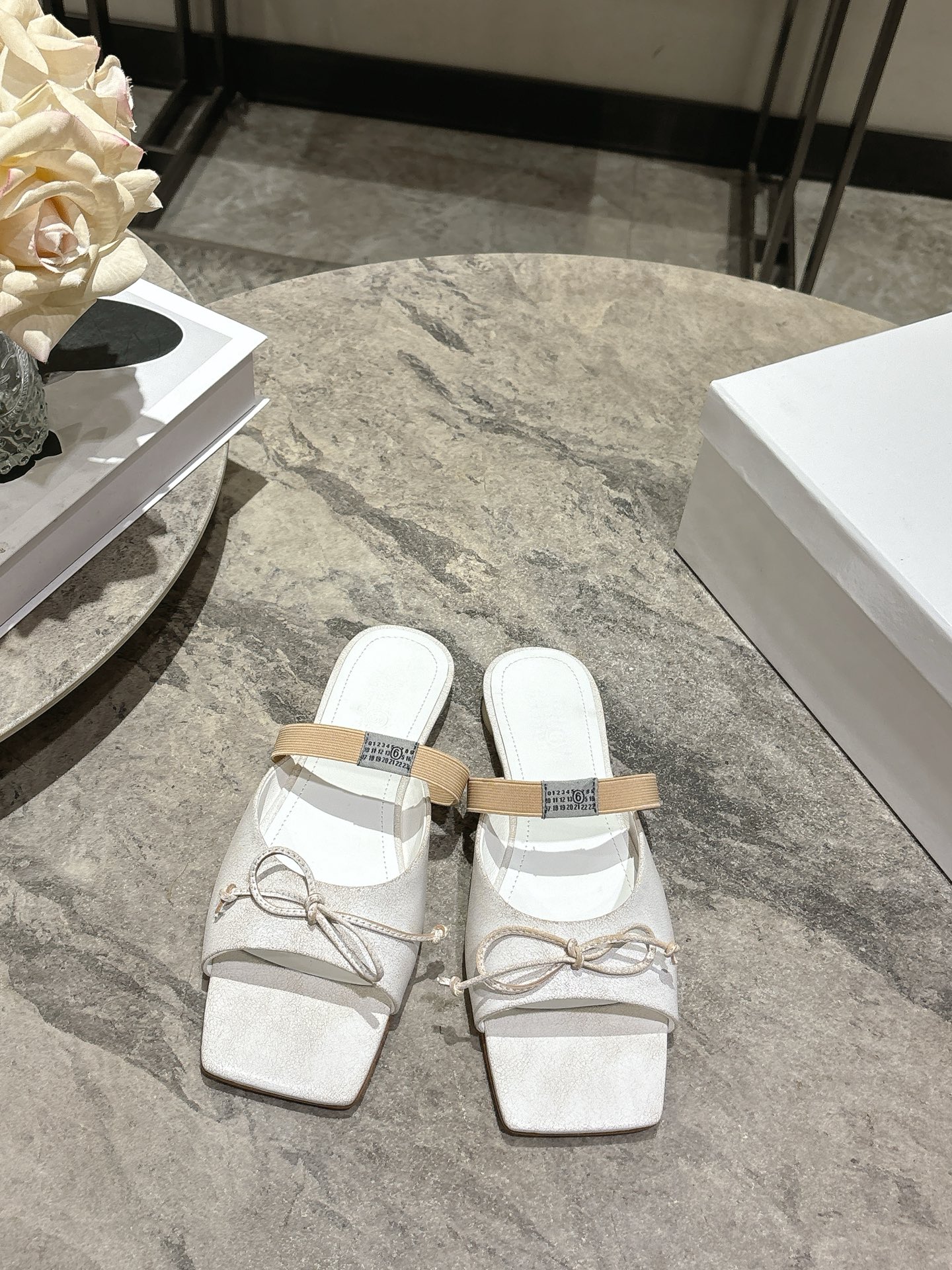 NO:707615,Maison Margiela's 26 spring and summer retro square toe elastic strap ballet flats spring shoe series adopts the brand's iconic sculptural silhouette that fits the shape of the foot. The upper is soft and smooth, taking into account both fit and design. The square toe + ballet elements are combined with the classic square toe design to create a modern feel. It is paired with the bow decoration on the upper to reconstruct the elegant outline of the ballet shoes. At the same time, it is made into a back-sliding style with mules, which is both casual and refined.  There is the iconic white single-thread stitching on the heel, and the elastic strap of the shoe body has the MM6 digital logo, which is the key to brand recognition. The empty mule slip structure simplifies the way of putting on and taking off, combining the softness of ballet shoes with the casualness of mule shoes. Retro cowhide upper, silk sheepskin lining, genuine leather outsole, high-heeled model 1cm size: 35-41 sizes (customized sizes 40 and 41 are not returnable), slippers ballet shoes, masion  margiela,masion margiela,flats,slippers,cowhide,sheepskin,Leather soles19860909Maison Margiela 马吉拉26春夏款复古方头弹力带芭蕾鞋平底鞋春鞋系列 采用品牌标志性的贴合脚型的雕塑感轮廓,鞋面柔软且线条流畅,兼顾贴合度与设计感.方头+芭蕾元素融合经典方头设计打造现代感,搭配鞋面蝴蝶结装饰,重构芭蕾鞋的优雅轮廓,同时做穆勒拖的后空款式,兼具休闲与精致. 鞋后跟处有标志性的白色单线缝线,鞋身弹性带带有MM6数字标识,是品牌辨识度的关键.后空的穆勒拖结构,简化穿脱方式,将芭蕾鞋的柔美与穆勒鞋的随性结合. 鞋面复古牛皮 内里丝绸羊皮里 大底真皮大底 高跟款1cm size :35-41码（40、41码定制不退换）,拖鞋芭蕾舞鞋,masion margiela,masion margiela,flats,slippers,cowhide,sheepskin,Leather soles,Women's Shoes