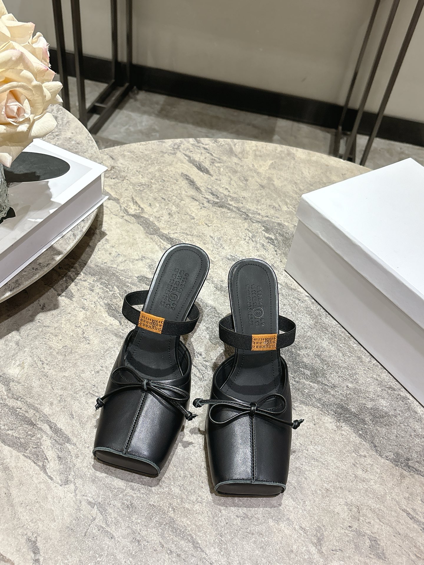 NO:707617,Maison Margiela's 26 spring and summer retro square toe elastic strap ballet flats spring shoe series adopts the brand's iconic sculptural silhouette that fits the shape of the foot. The upper is soft and smooth, taking into account both fit and design. The square toe + ballet elements are combined with the classic square toe design to create a modern feel. It is paired with the bow decoration on the upper to reconstruct the elegant outline of the ballet shoes. At the same time, it is made into a back-sliding style with mules, which is both casual and refined.  There is the iconic white single-thread stitching on the heel, and the elastic band of the shoe body has the MM6 digital logo, which is the key to brand recognition. The empty mule slip structure simplifies the way of putting on and taking off, combining the softness of ballet shoes with the casualness of mule shoes. Retro cowhide upper, silk sheepskin lining, leather outsole, high-heeled model 7cm size: 35-41 sizes (customized sizes 40 and 41 are not returnable), slippers ballet shoes, masion  margiela,masion margiela,flats,slippers,cowhide,sheepskin,Leather soles19860909Maison Margiela 马吉拉26春夏款复古方头弹力带芭蕾鞋平底鞋春鞋系列 采用品牌标志性的贴合脚型的雕塑感轮廓,鞋面柔软且线条流畅,兼顾贴合度与设计感.方头+芭蕾元素融合经典方头设计打造现代感,搭配鞋面蝴蝶结装饰,重构芭蕾鞋的优雅轮廓,同时做穆勒拖的后空款式,兼具休闲与精致. 鞋后跟处有标志性的白色单线缝线,鞋身弹性带带有MM6数字标识,是品牌辨识度的关键.后空的穆勒拖结构,简化穿脱方式,将芭蕾鞋的柔美与穆勒鞋的随性结合. 鞋面复古牛皮 内里丝绸羊皮里 大底真皮大底 高跟款7cm size :35-41码（40、41码定制不退换）,拖鞋芭蕾舞鞋,masion margiela,masion margiela,flats,slippers,cowhide,sheepskin,Leather soles,Women's Shoes